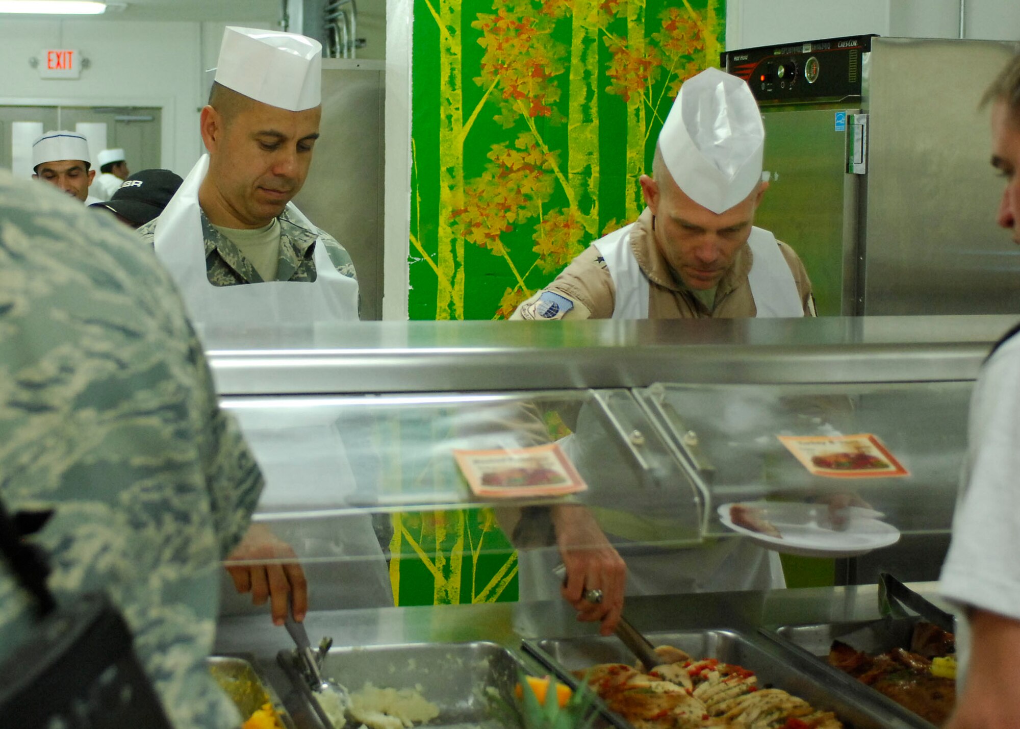 BAGRAM AIRFIELD, Afghanistan -- Chief Master Sgt. Jeffery Cui (left), 455th Air Expeditionary Wing command chief, and Brig. Gen. Steven Kwast (right), 455th Air Expeditionary Wing commander, serve Airmen food during a Thanksgiving day celebration, Nov. 26, 2009.  455th AEW's leadership served meals on Thanksgiving as a way to boost the morale of the servicemen and women.  (U.S. Air Force photo/Senior Airman Felicia Juenke)