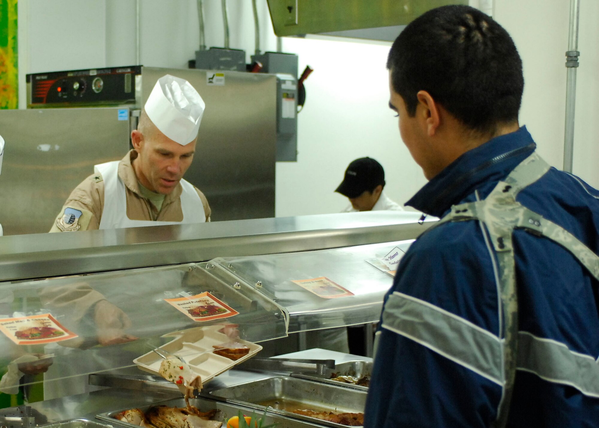 BAGRAM AIRFIELD, Afghanistan -- Brig. Gen. Steven Kwast (right), 455th Air Expeditionary Wing commander, serves an Airman food during a Thanksgiving day celebration, Nov. 26, 2009.  455th AEW's leadership served meals on Thanksgiving as a way to boost the morale of the servicemen and women.  (U.S. Air Force photo/Senior Airman Felicia Juenke)
