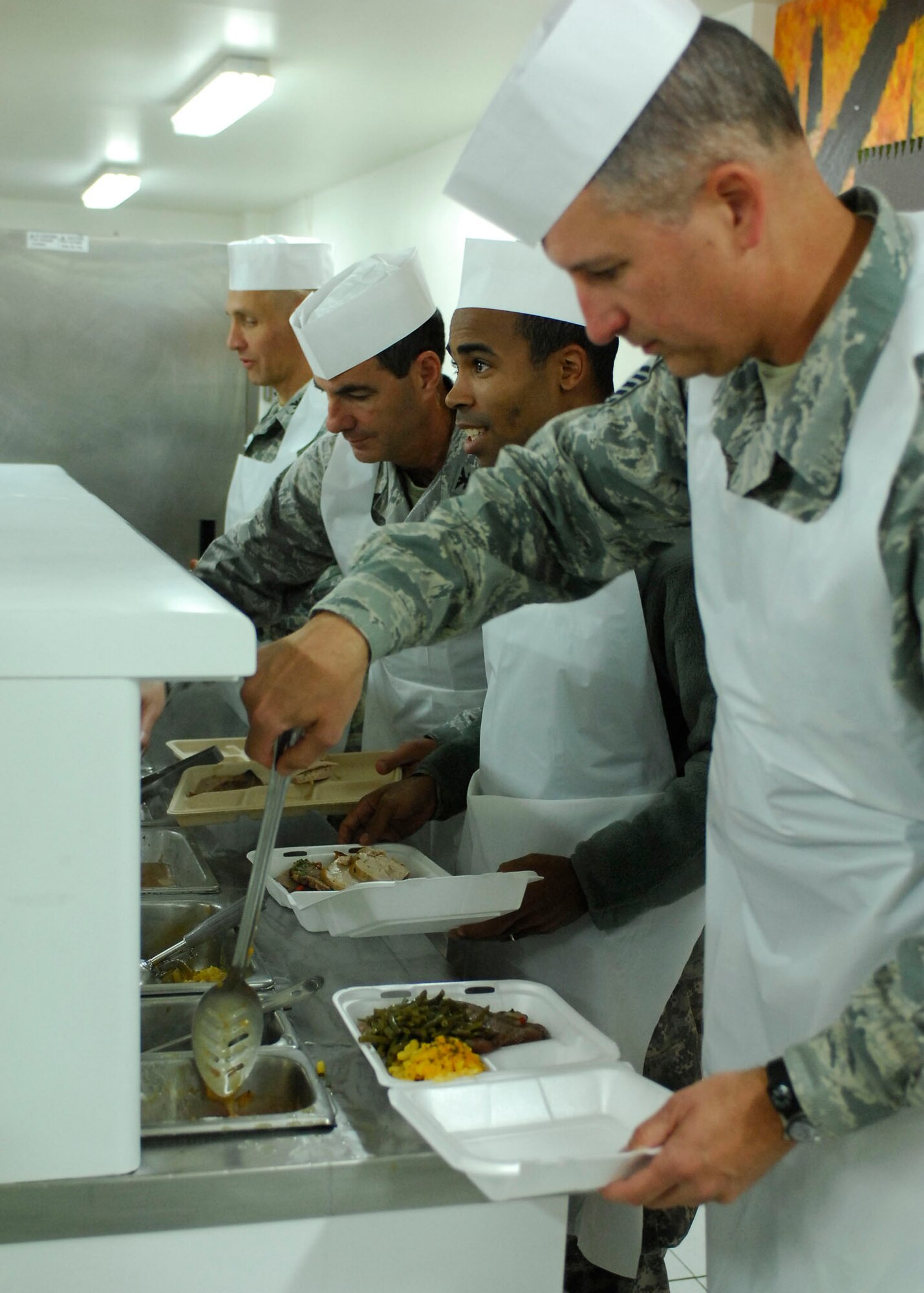 BAGRAM AIRFIELD, Afghanistan -- Senior Master Sgt. Philip Gaudette (right), the 455th Expeditionary Civil Engineering Squadron first sergeant, serves an Airman food during a Thanksgiving celebration, Nov. 26, 2009.  Air Force and Army leadership served meals on Thanksgiving as a way to boost the morale of the servicemen and women.  Sergeant Gaudette is deployed from McGuire Air Force Base, N.J., and hails from the Bronx, N.Y.  (U.S. Air Force photo/Senior Airman Felicia Juenke)