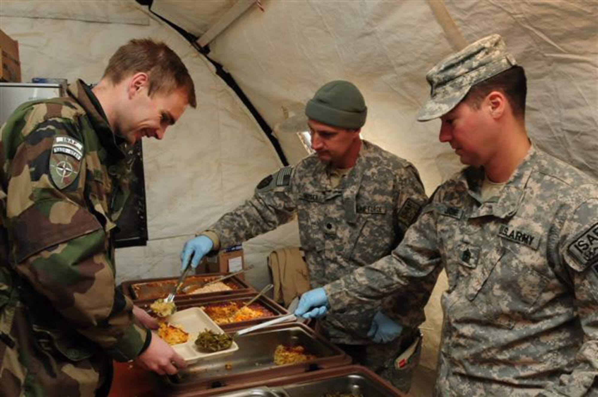 Forward Operating Base Morales-Frazier -- U.S. Air Force Lt. Col. W.M. Heiser (center,) serves food to an unidentified French soldier on Thanksgiving day Nov. 26, 2009 while U.S. Army First Sergeant Earl Jones (right) assists.  Colonel Heiser is the commander of Provincial Reconstruction Team Kapisa, a joint team of Soldiers and Airmen who work to increase infrastructure and governance in Afghanistan's Kapisa province.  Colonel Heiser, originally from Atlanta, Ga., is deployed to Afghanistan from Joint Forces Command.  (U.S. Air Force photo/Captain Darrick Lee)