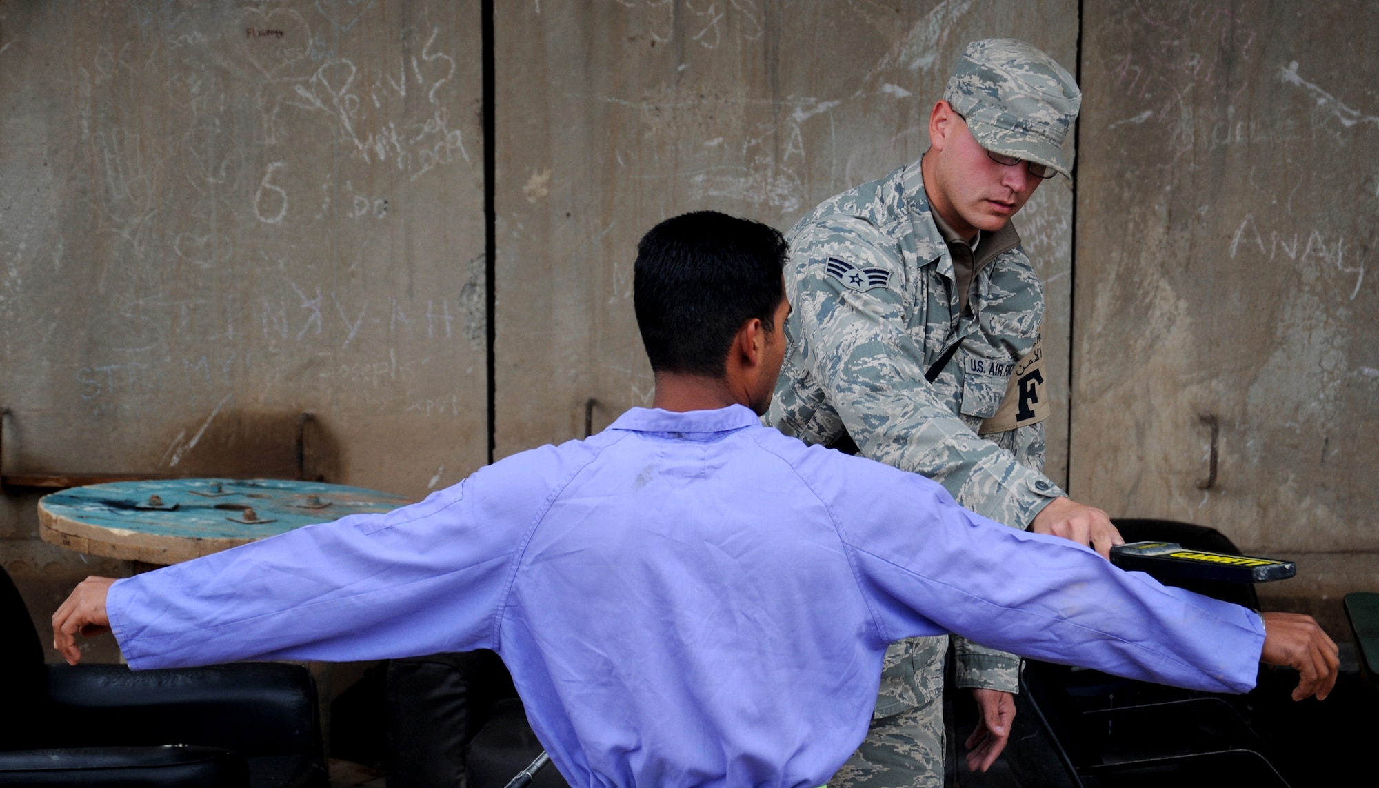 JOINT BASE BALAD, Iraq -- Senior Airman Ruben Lopez, 332nd Expeditionary Civil Engineer Squadron force protection escort, checks local nationals for weapons or prohibited items as they enter the gravel yard Nov. 19, 2009. Airmen deployed as FP escorts protect resources while providing safety and security on JBB. (U.S. Air Force photo/Senior Airman Christopher Hubenthal) 