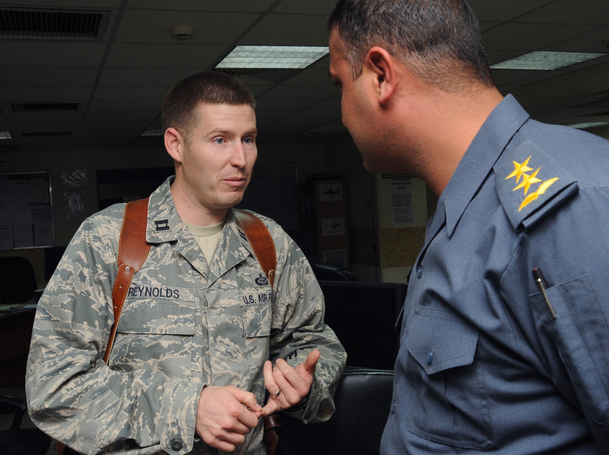 CAMP VICTORY, Iraq -- Air Force Captain Sean Reynolds, Iraq Training and Advisory Mission - Iraqi Air Operations Center intelligence advisor, speaks Arabic with an Iraqi air force officer Nov. 25, 2009. The prior-enlisted officer served as an Arabic linguist for seven years and says understanding the language has helped facilitate communication throughout the IAOC. Captain Reynolds is deployed from Goodfellow Air Force Base, Texas, and hails from San Diego, Calif. (U.S. Air Force photo/Tech. Sgt. Johnny L. Saldivar)