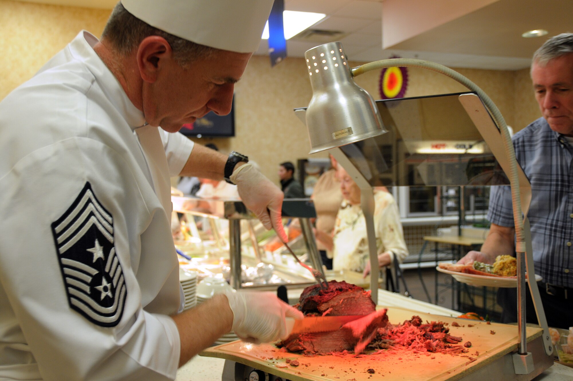 EGLIN AIR FORCE BASE, Fla. – Chief Master Sgt. Thomas Westermeyer, 96th Air Base Wing and Air Armament Center command chief, carves up roast beef for customers at the Eglin Breeze Dining Facility for Thanksgiving, Nov. 26. Turkey, ham and all the trimmings were available to Eglin Airmen, dependants, visiting family members and retirees. The facility prepared food in anticipation for about 550 guests. (U.S. Air Force photo/Airman 1st Class Anthony Jennings)