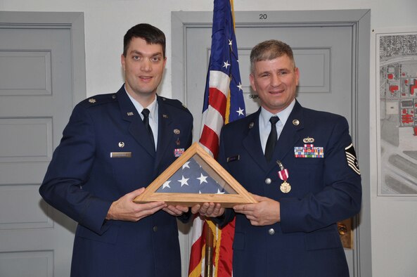 Master Sgt. Richard Loesch receives a ceremonial retirement flag from Lt. Col. Rick Erredge, 934th Communications Flight commander. (Air Force photo/Tech. Sgt. Bob Sommer)