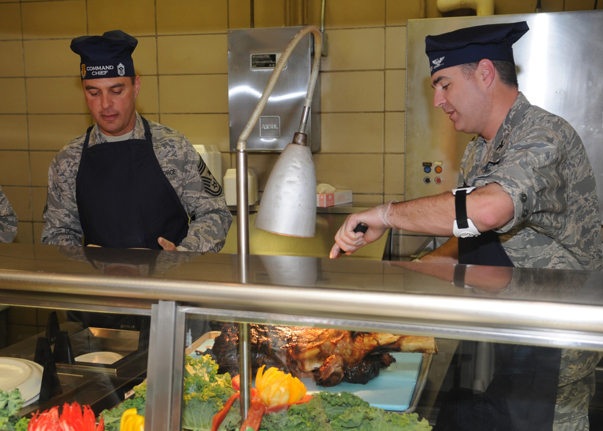 GOODFELLOW AIR FORCE BASE, Texas -- Chief Master Sgt. Frederick Ricker, 17th Training Wing command chief master sgt., and Col. Thomas Geary, 17th TRW commander, serve a traditional Thanksgiving meal at the Western Winds Dining Facility, Nov. 26, 2009. Each Thanksgiving leadership from the various units on base assists with serving the meal to dorm residents and others who remain on base during the holiday. (U.S. Air Force photo/Airman Clayton Lenhardt)
