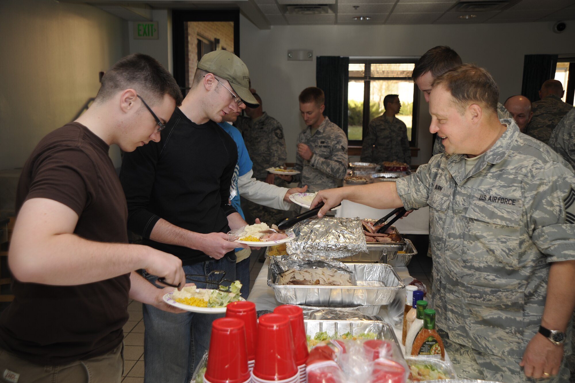 Chief Master Sgt. Stephen Burn (right), 21st Comptroller Squadron, serves food to Airmen at the annual Thanksgiving meal, Nov. 20. The event was hosted by the Combined First Sergeants Council and the Colorado Springs Chief’s Group who set up and served food to Airmen living in the dorms before the Thanksgiving holiday. (Air Force photo by Craig Denton)

