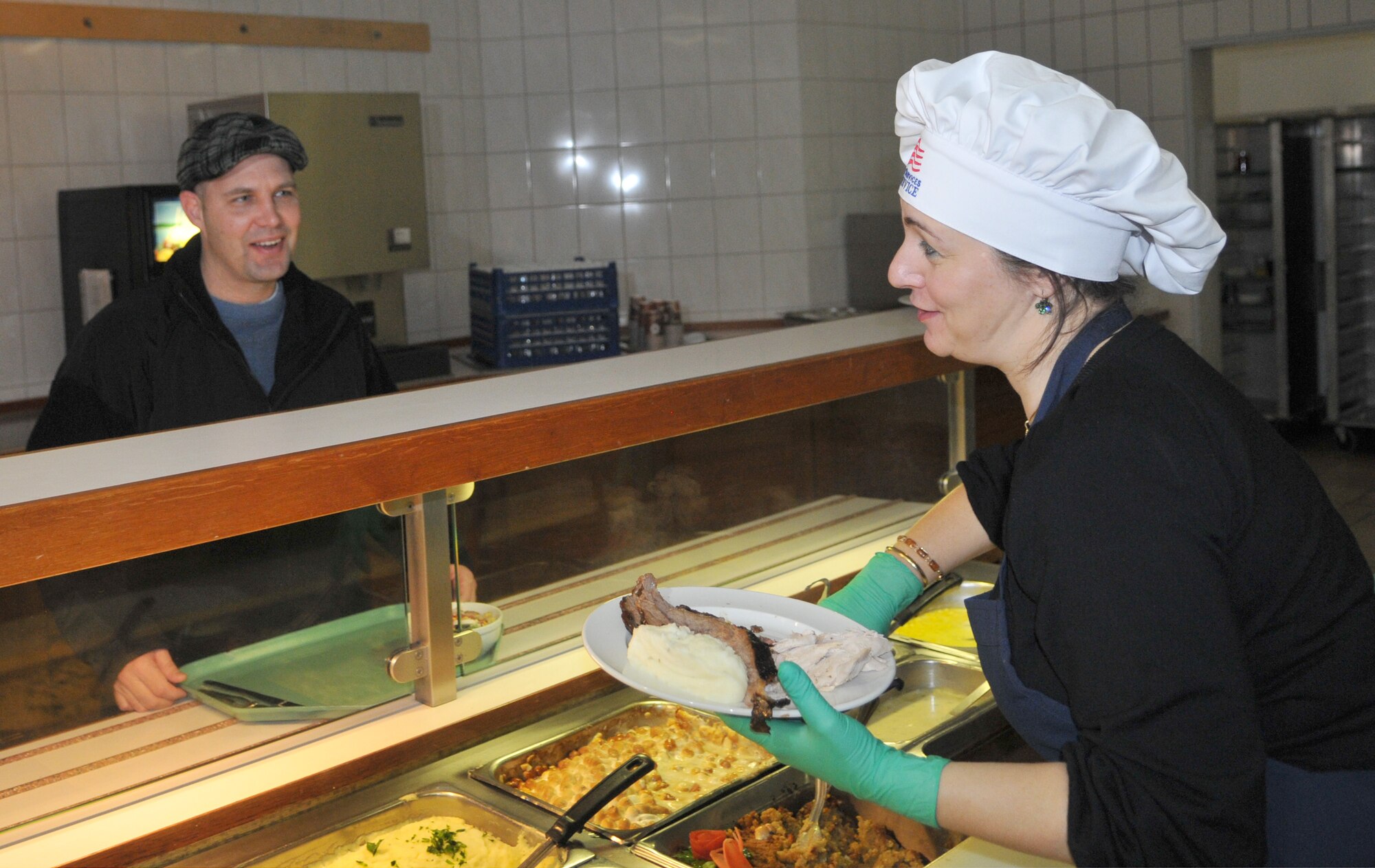 SPANGDAHLEM AIR BASE, Germany -- Mara Wight, wife of Col. Tip Wight, 52nd Fighter Wing commander, gives a Thanksgiving plate to Senior Master Sgt. Earle Babb, 52nd Aircraft Maintenance Squadron, Nov. 26. Members of the 52nd FW leadership and several other volunteers hosted this year's Thanksgiving meal at the Mosel Dining Facility. (U.S. Air Force photo/Airman 1st Class Nick Wilson)