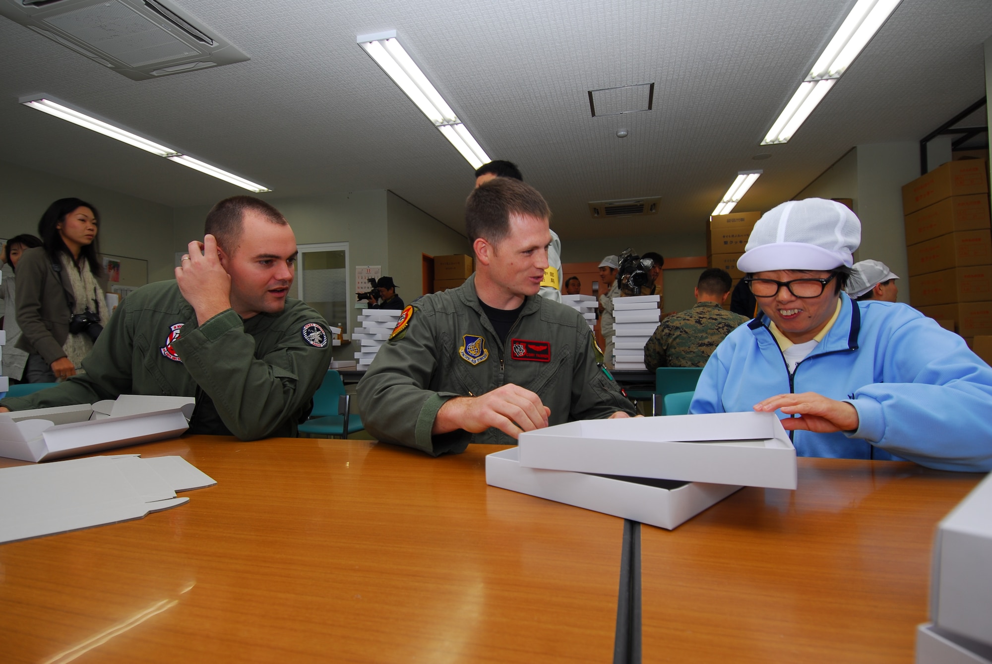KOMATSU AIR BASE, Japan—Misako Hatta, Umenoki Gakuen student, shows Marine Capt. Ted Fienning, Marine Corps All-Weather Fighter Attack Squadron 533 F/A-18D Hornet pilot, and Air Force Capt. Cory Farrer, 13th Fighter Squadron F-16 Fighting Falcon pilot, the proper way to fold a candy box Nov. 19 at a Komatsu, Japan, welfare center. Airmen and Marines had an opportunity to visit with the local community during the Komatsu Alternate Training Relocation Exercise. (U.S. Air Force photo/Staff Sgt. Phillip Butterfield)