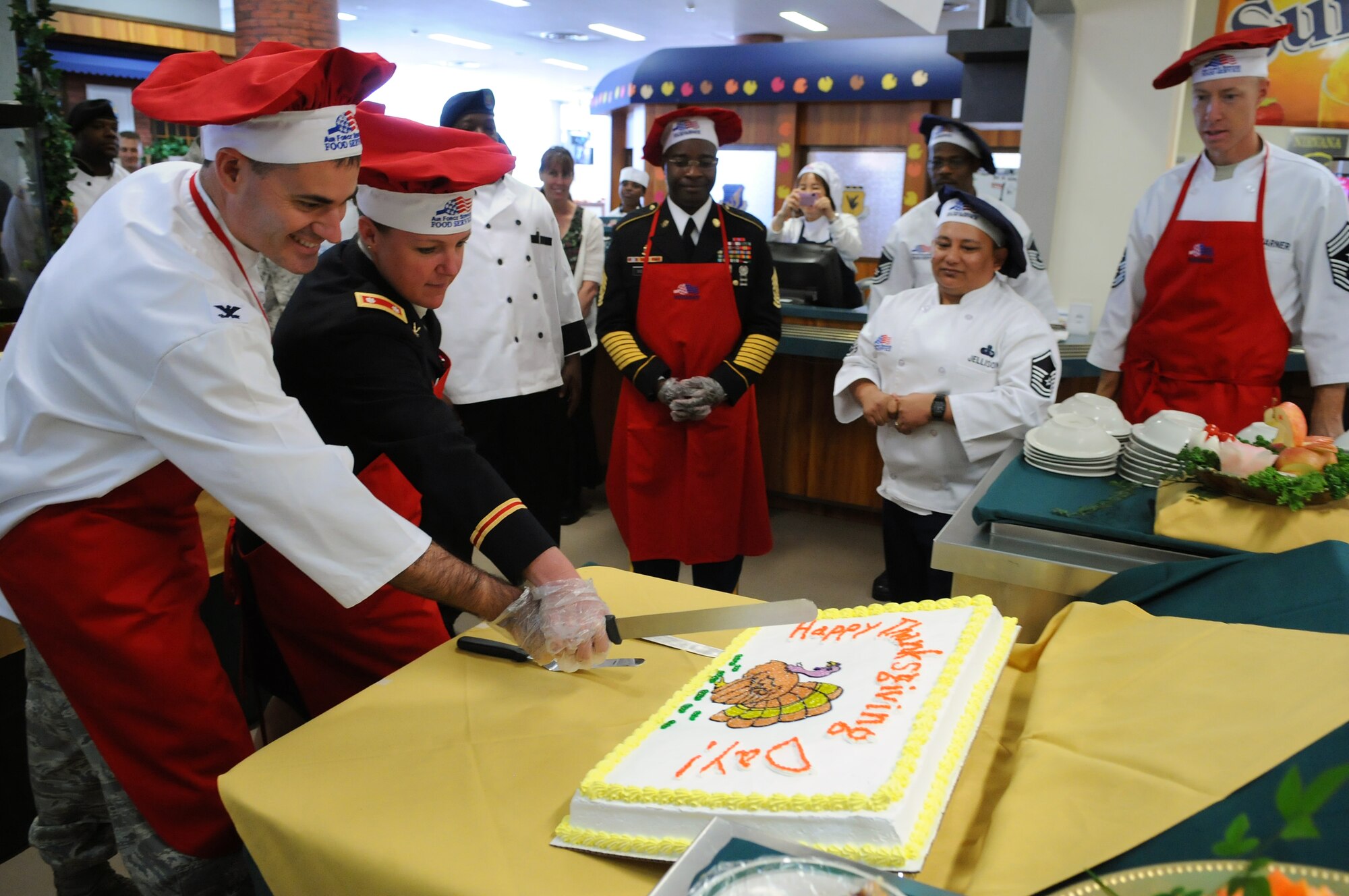 Col. Lenny Richoux, 18th Wing vice commander and Lt. Col. Janell Eickoff, 1-1 Air Defense Artillery commander, cut a Thanksgiving cake before serving it to dorm residents at the Marshall Dining Facility at Kadena Air Base, Japan, Nov. 26. Every year, the 18th Force Support Squadron provides dormitory residents the opportunity to enjoy a homemade holiday meal. 
(U.S. Air Force photo/Airman First Class Amanda Grabiec)