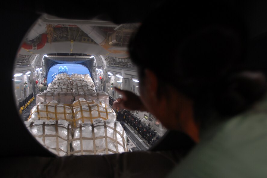 HICKAM AIR FORCE BASE, Hawaii -- Capt. B.J. Itoman, a Hawaii Air National Guard C-17 pilot, watches as humanitarian aid supplies from the Federal Emergency Management Agency is loaded by Hawaii Air National Guard, Hawaii National Guard and Hickam Active Duty Airmen into a C-17 Globemaster III bound for American Samoa to assist in the relief efforts underway Sept 30. The efforts are in the wake of tsunamis triggered by an undersea earthquake Sept. 29 that has left more than 140 people dead in the South Pacific region. More than 90 Airmen and Soldiers deployed from Hawaii for the humanitarian mission. (U.S. Air Force photo/Staff Sgt. Mike Meares)