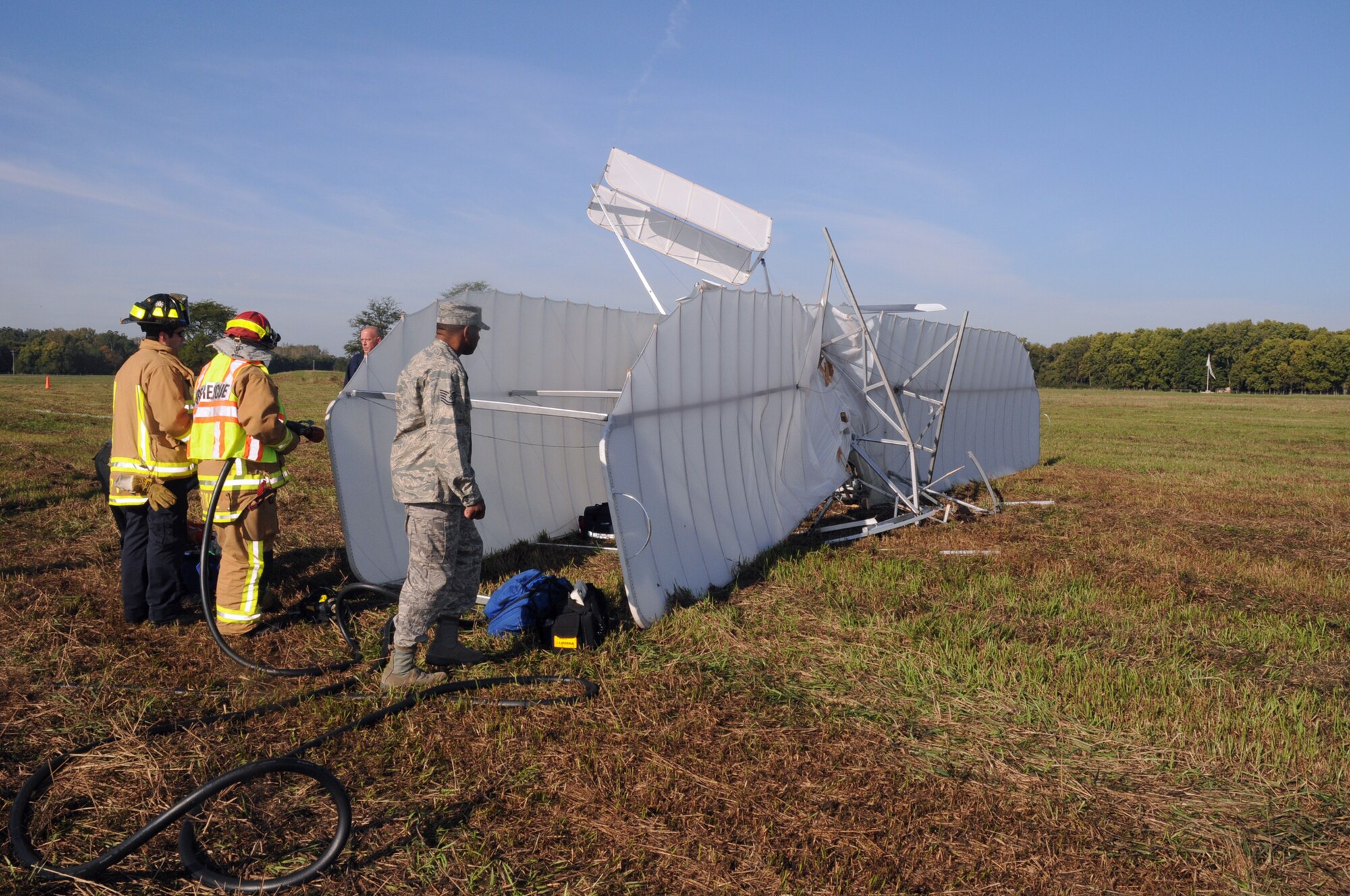 Air Force crash rescue and safety personnel inspect the wreckage of a replica 1905 Wright Flyer III that crashed Oct. 1, 2009 on Huffman Prairie Flying Field at Wright-Patterson Air Force Base, Ohio.  Pilot and vintage aircraft builder Mark Dusenberry of Dennison, Ohio was injured during the practice flight in preparation to celebrate the 104th Anniversary of Practical Flight. (Air Force photo/Al Bright)
