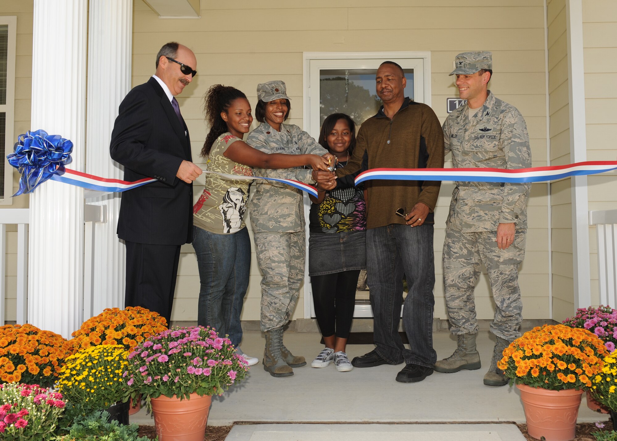 LANGLEY AIR FORCE BASE, Va. -- Maj. Paula Chavis, 1st Inpatient Operations Squadron, and her family cut the ribbon to their new house with the help of Col. Matt Molloy, 1st Fighter Wing commander, here Sep. 30. The Chavez family is the first family to have a new house in the in the Jamestown Village section of Landings at Langley at Bethel Manor. (U.S. Air Force photo/Airman1st Class John Teti)
