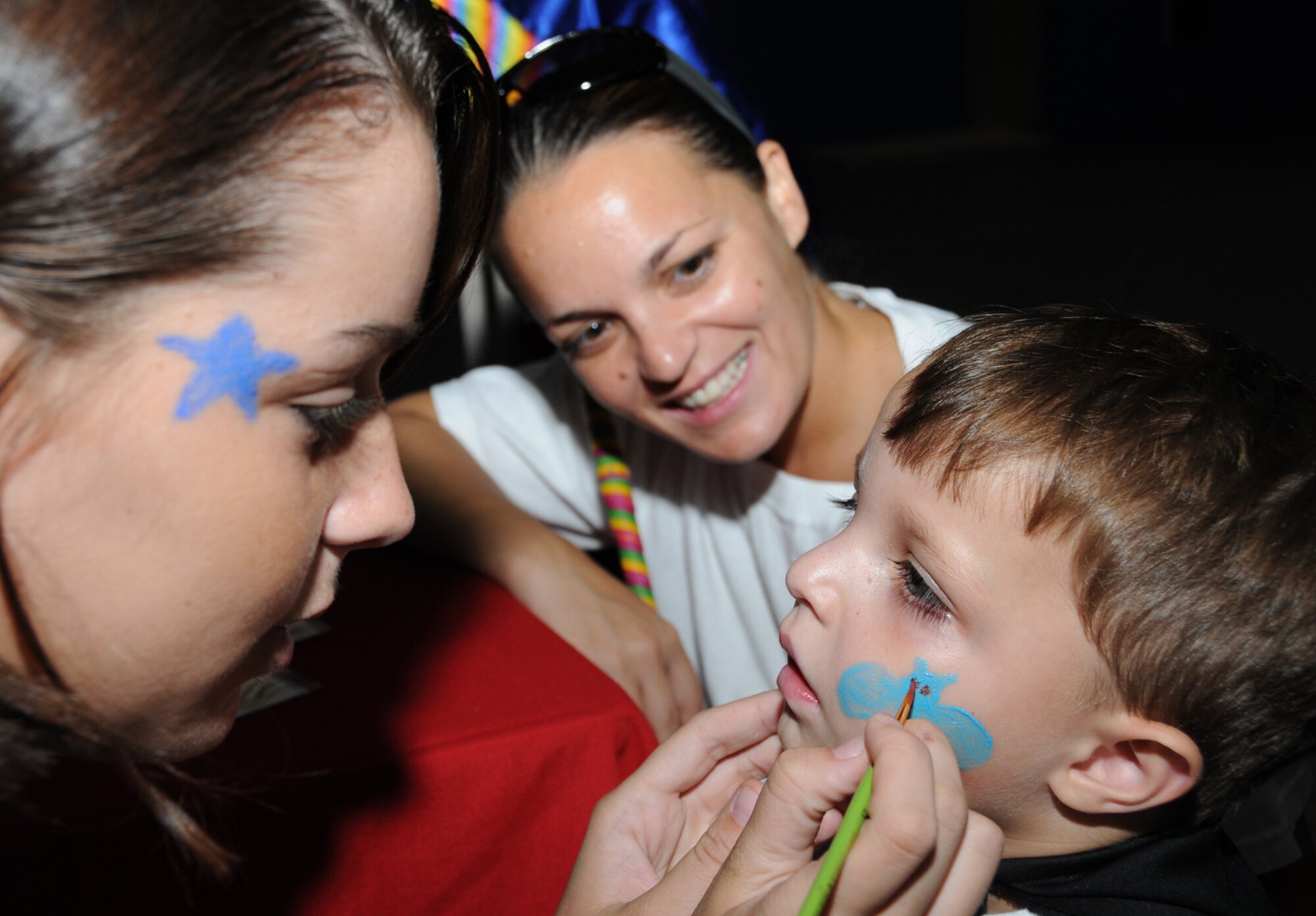 Airman Basic Taylor Monroe, 334th TRS, paints Matthew McNair, 3, as his mother, Venessa, looks on. Matt’s father is Tech. Sgt. Donald McNair, 334th TRS.  (U.S. Air Force photo by Kemberly Groue)