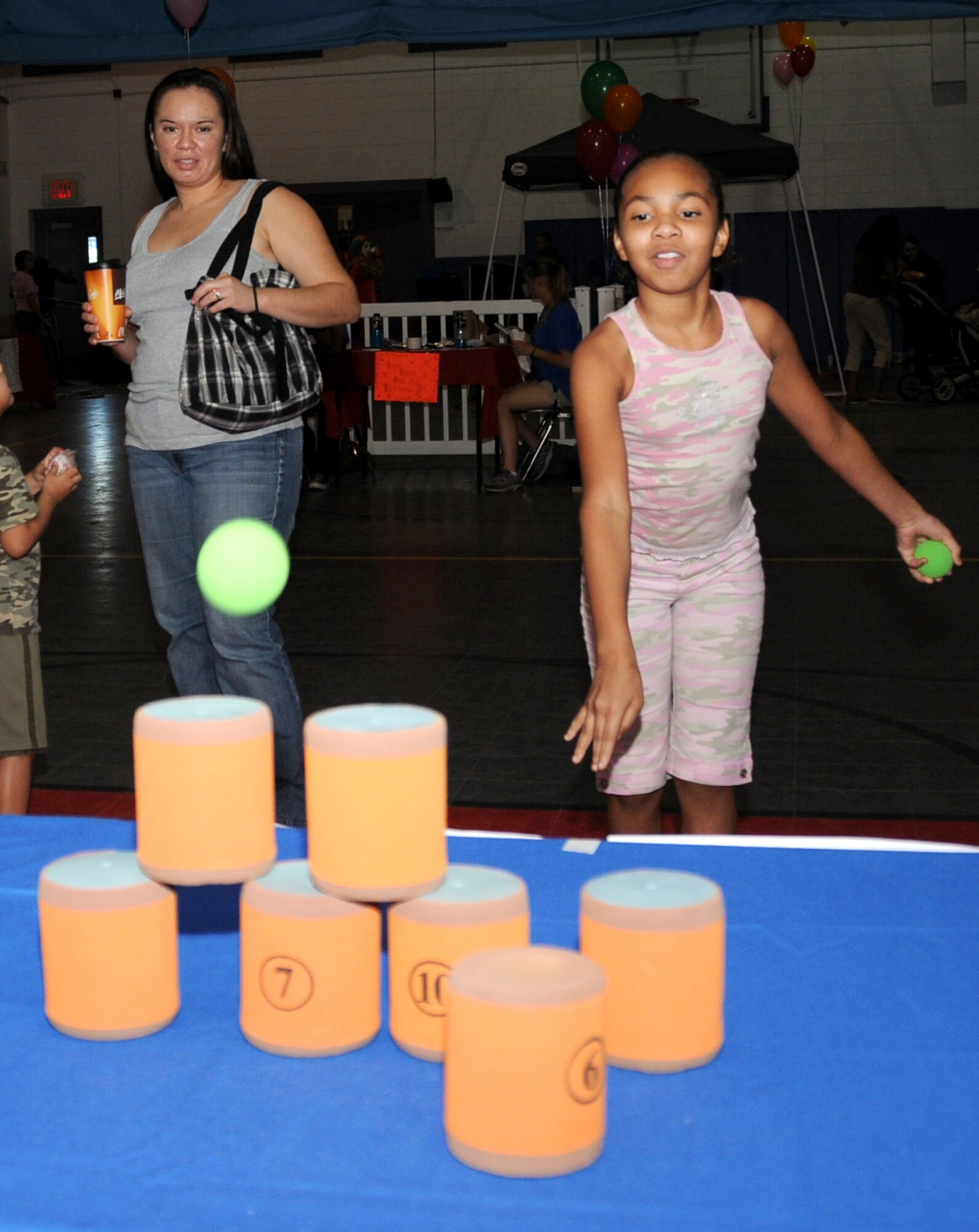 Maria Galindo, at left, watches daughter, Dejah, 9, play a game.  Dejah’s dad, Senior Airman Leo Galino is deployed to Korea from the 81st Logistics Readiness Squadron.   Children of deployed parents were special guests at the event.  (U.S. Air Force photo by Kemberly Groue)