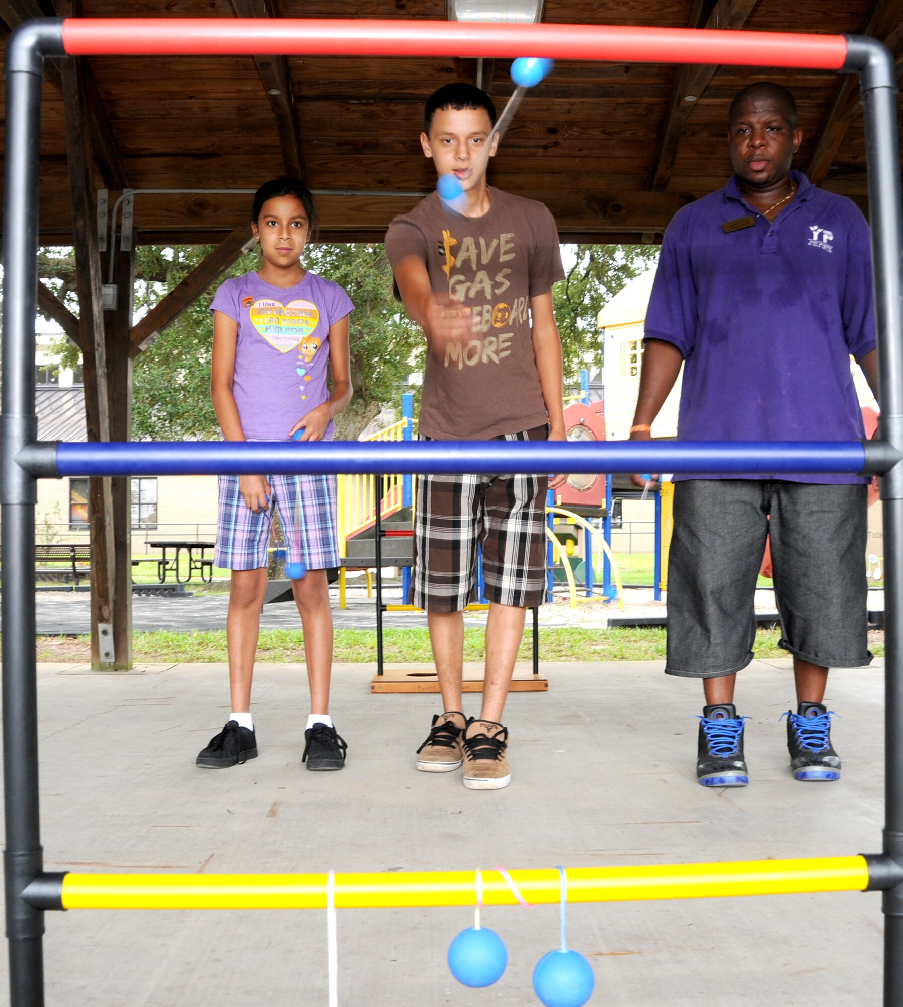 Michelle Gelacio, 11,  left, and Alex Galacio, 15, try their luck with a game, while Lonnald Carter, 81st Force Support Squadron, cheers them on. Michelle and Alex's parents are Tech. Sgt. Jesus and Dora Gelacio. 81st LRS.  Sergeant Galacio is deployed to Iraq.  (U.S. Air Force photo by Kemberly Groue)