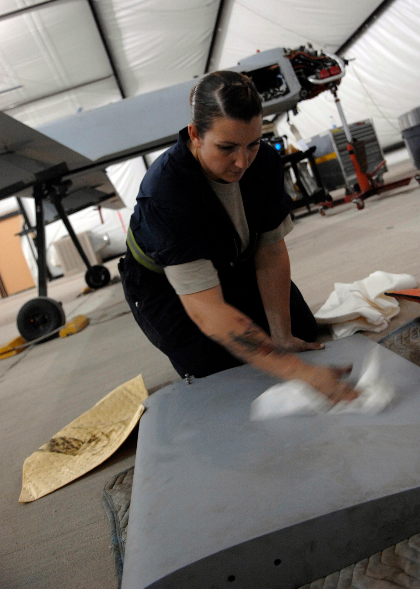 Senior Airman Valerie Santa wipes down an MQ-1 Predator's vertical stabilizer during an engine rebuild while performing maintenance here, Sept. 23, 2009. Airman Santa is using an alcohol-based chemical to cut through grease that has built up on the surface that water cannot disolve. Airman Santa is a crew chief for the 62nd Expeditionary Reconnaissance Squadron from Creech Air Force Base, Nev. and hails from Apple Valley, Calif. (U.S. Air Force photo/Senior Airman Timothy Taylor)