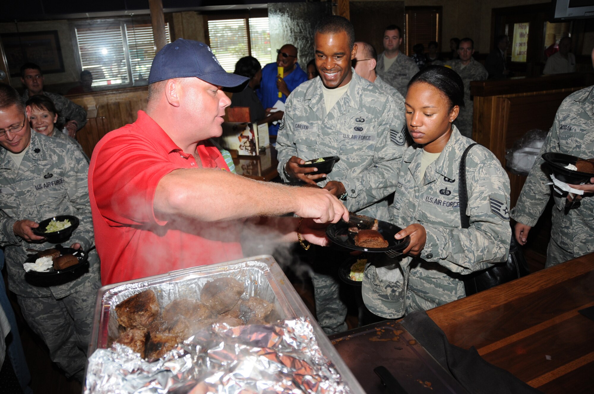Chief Master Sgt. Mike Skidmore, 81st Aerospace Medicine Squadron, serves Tech. Sgt. Stephen Carter, 81st Comptroler Squadron, and Staff Sgt. Latonya Carter, 334th Training Squadron, at the Keesler Chiefs Group steak sale Friday at Outback Steakhouse in D’Iberville.  The annual event provides NCO Academy awards and scholarships for Community College of the Air Force students.  (U.S. Air Force photo by Kemberly Groue)