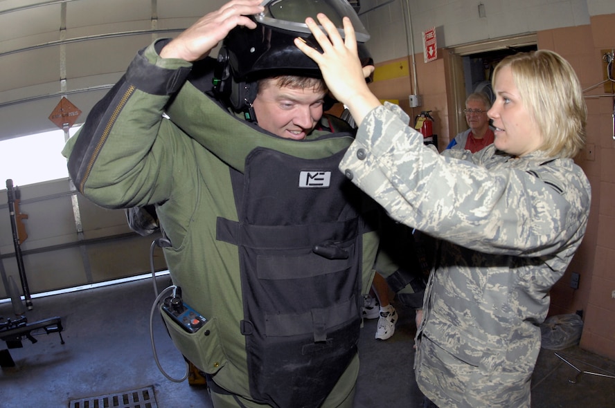 MINOT AIR FORCE BASE, N.D. -- Senior Airman Emily Walker, 5th Civil Engineer Squadron explosive ordinance disposal technician, helps Jason Young, a New Salem, N.D. city council member, into an EOD Type 9 bomb suit to simulate the gear her and her team use when utilizing the training and tactics they have learned throughout their careers to members of the League of Cities at the EOD unit Sept. 25 here. Group tours such as these continue the growing friendship between Minot AFB and its surrounding communities all across the state. (U.S. Air Force photo by Airman 1st Class Benjamin Stratton)