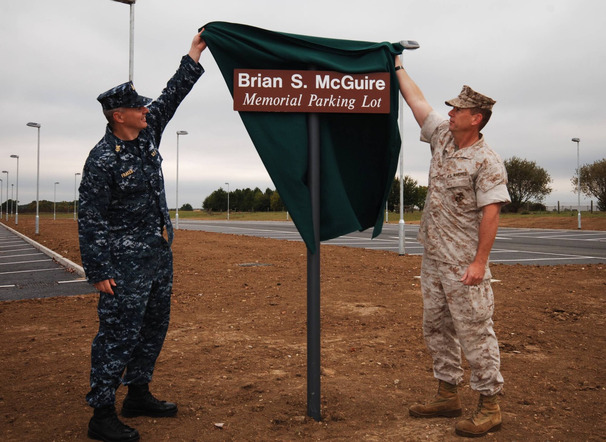JIOCEUR Senior Enlisted Leader, Navy Master Chief John C. Frakes and JAC Commander, Marine Corps Col. Pete Devlin unveil the sign designating the new Lt. Col. Brian S. McGuire parking lot on September 29, 2009.  The lot honors the memory of McGuire and his work in support of the legacy of the 303rd Bomb Group, which flew from Molesworth, during WWII. His contributions included funding and building the 303rd Memorial at the gate to the base.  (U.S. Air Force photo by Staff Sgt. Rachel A. Goff)