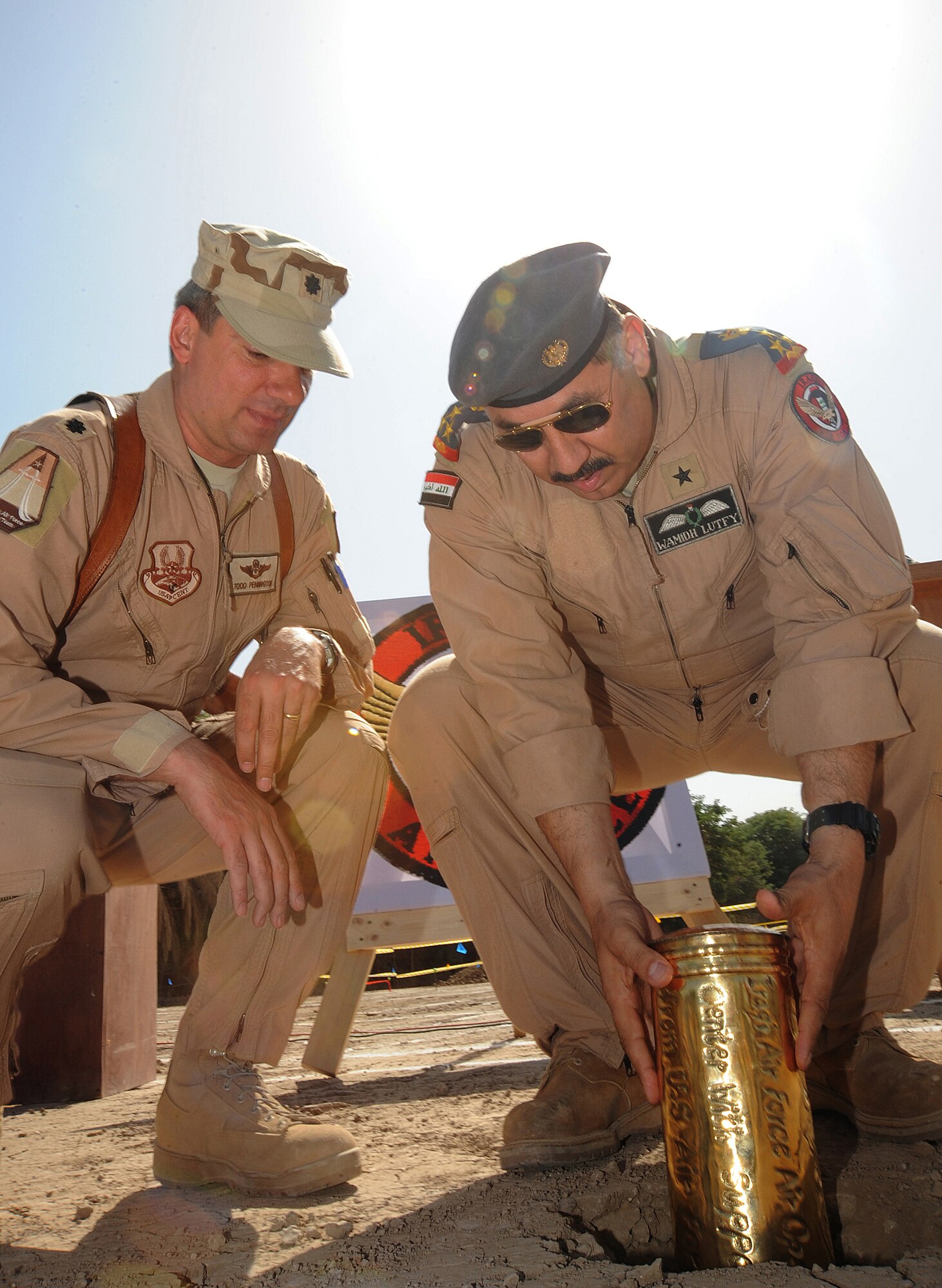 HAWK BASE, Iraq -- Air Force Lt. Col. Todd Pennington, Iraqi Training and Advisory Mission - Air Force air operations center chief, and Staff  Brig. Gen. Wamidh, Iraqi Air Force director of operations, bury a time capsule during the Iraqi AOC ground breaking ceremony here Sept. 30, 2009. The time capsule contains candid photographs of Iraqi and U.S. AOC personnel and will be buried under the foundation of the new Iraqi AOC.  The facility will play a vital role in the growth and future success of the Iraqi air force and maintaining a secure, stable, and sovereign Iraq. (U.S. Air Force photo/Tech. Sgt. Johnny L. Saldivar)