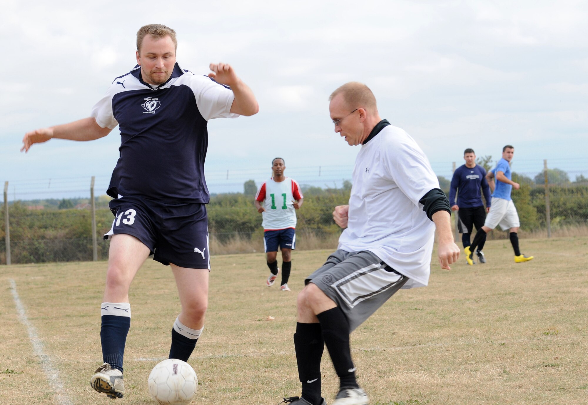 RAF MILDENHALL, England -- George Patsios, 488th Intelligence Squadron player (left), runs down the wing, dribbling past John Host, 100th Logistics Readiness Squadron player, in an intramural soccer match near the Hardstand Fitness Center here Sept. 30. The 100th LRS scored three points in a five-minute overtime session to take the match 6-3 against the combined 488th IS/95th Reconnaissance Squadron team. (U.S. Air Force photo/Senior Airman Thomas Trower) 
