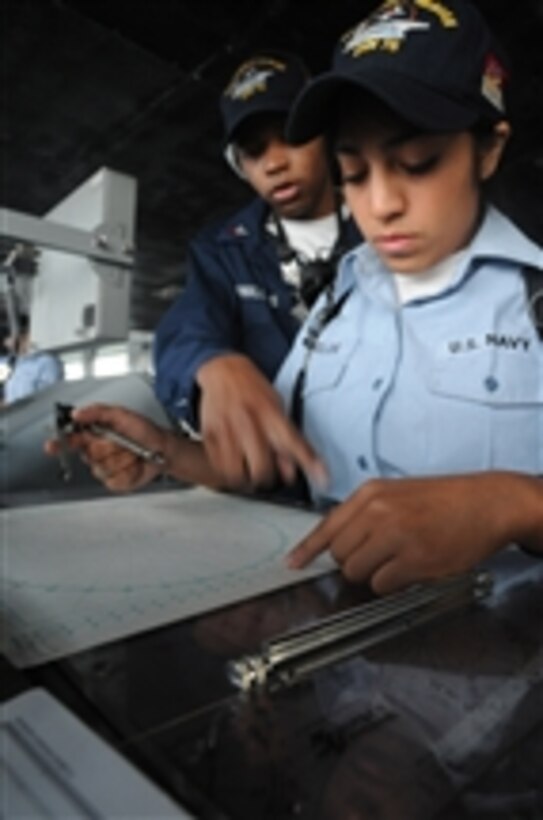 U.S. Navy Petty Officer 2nd Class Donald Phillips (left) assists Seaman Lydia Banuelos with plotting a navigational chart on the bridge of the aircraft carrier USS Ronald Reagan (CVN 76) in the Gulf of Oman on Sept. 11, 2009.  