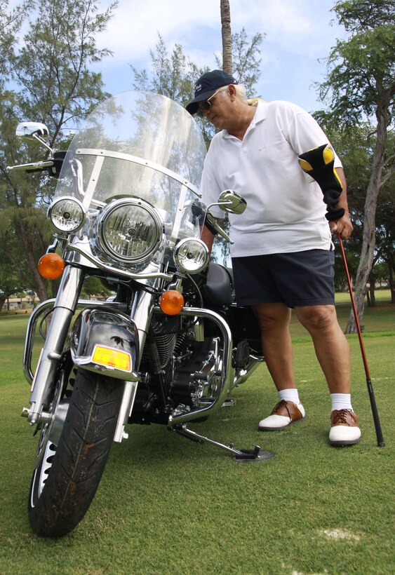 Randy Ebright, a Kailua resident, eyes a Harley-Davidson motorcycle to be given to any golfer who gets a hole-in-one at one of the holes at the Klipper Golf Course here during the U.S. Marine Corps Forces, Pacific golf scramble tournament Oct. 2. Civilians and military personnel enjoyed a day of golf and supported the MarForPac enlisted ball fund.