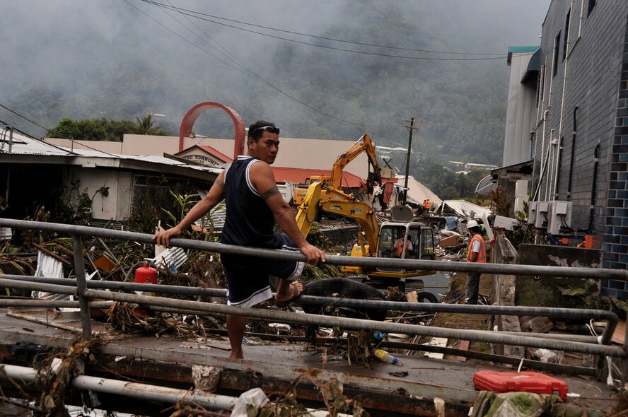 PAGO PAGO - A local American Samoan man looks over his shoulder while workers try to pick-up the trash and debris from a drainage area in Pago Pago on Oct. 1, 2009 after a tsunami caused a great amount of structural damage to the island and it's villages Sept. 29, 2009. (U.S.  Air Force photo/Tech Sgt. Cohen A. Young)
