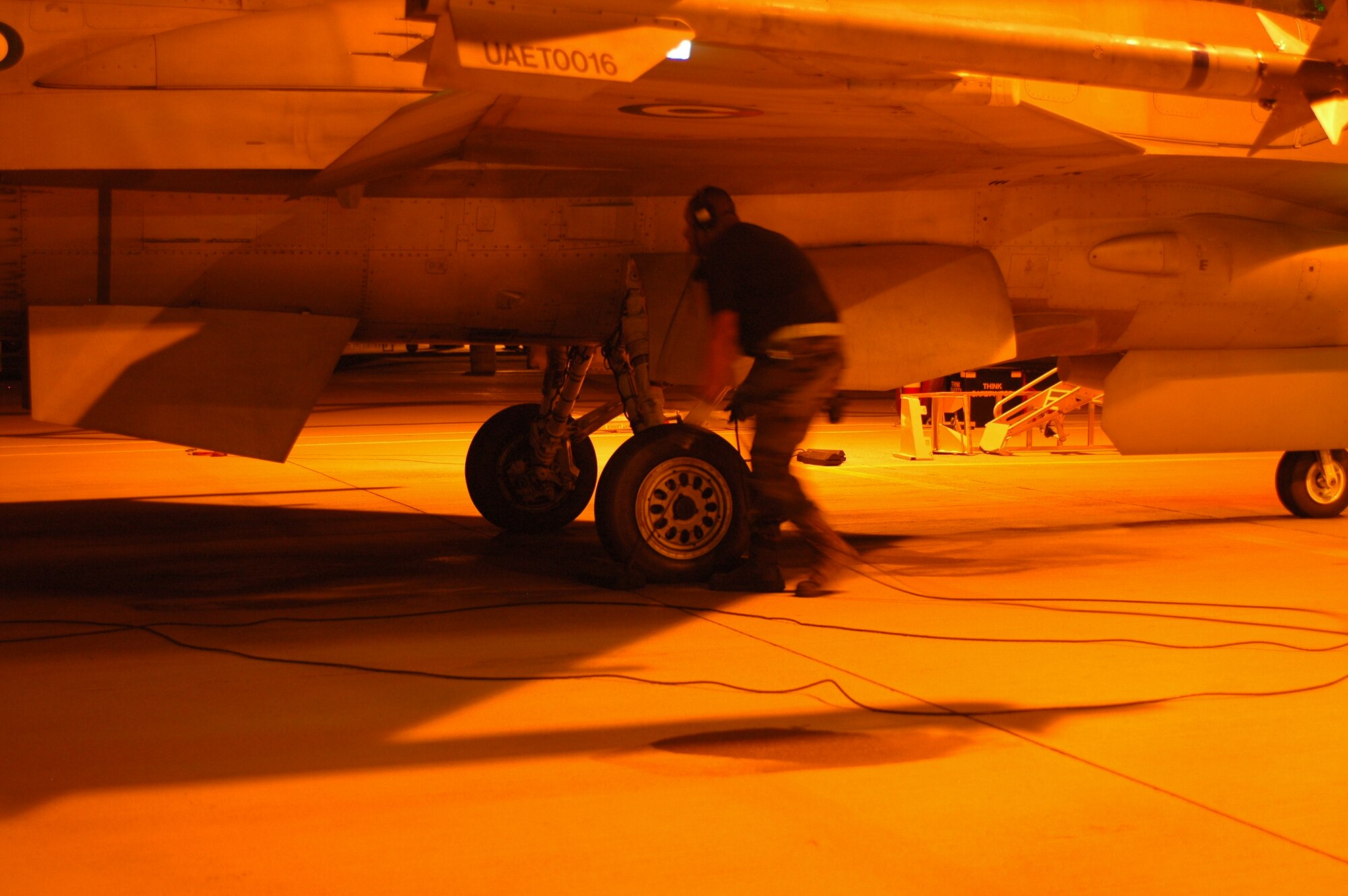 An F-16 crew chief prepares to pull chocks and launch his jet for a night mission. (Air National Guard photo by Maj. Gabe Johnson)