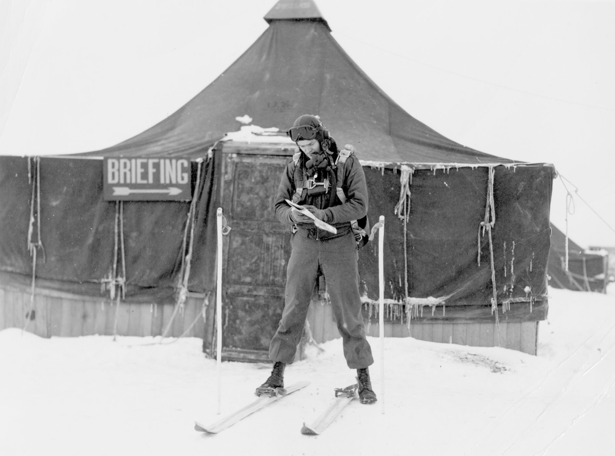 With no sidewalks or pathways on the rough airfield, Maj. George Brooking found it easier to use skis to go from the briefing tent to his P-47. (U.S. Air Force photo)