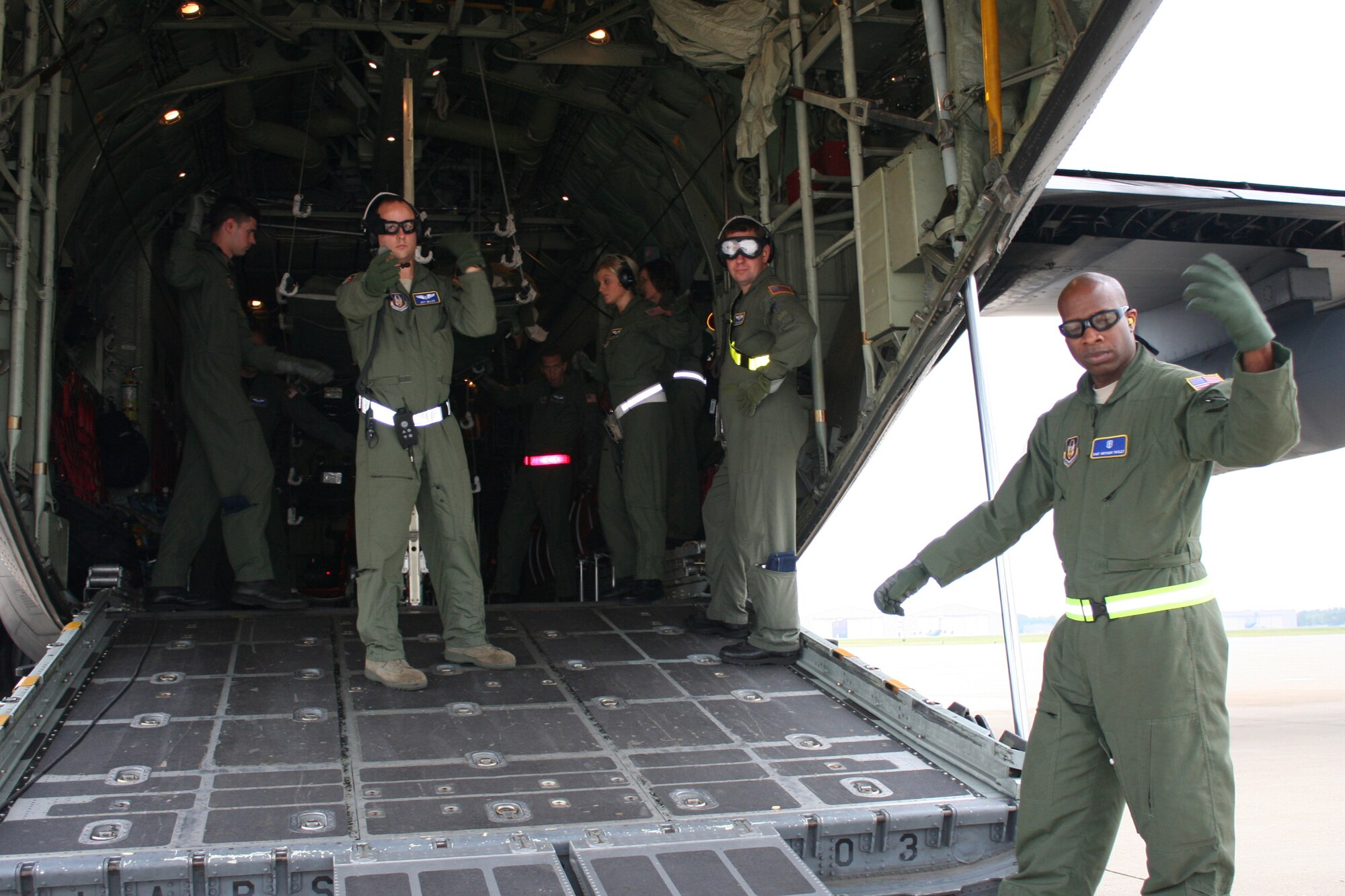 WRIGHT-PATTERSON AIR FORCE BASE, Ohio - Under the watchful eye of Maj. Todd Mulhorn (second from right), the training instructor for the exercise, 2nd Lt.  Jeffrey Miller (center), the medical crew director,  gives the signal along with Staff Sgt. Tony Pasley (forground) to the aeromedical evacuation operations officer to begin transferring patient litters to the waiting C-130 Hercules.  The reservists, all assigned to the 445th Aeromedical Evacuation Squadron, are taking part in a “hot load” training mission. Sixteen reservists altogether from AES participated in a three-day training event that involved loading and unloading patients and equipment onboard the aircraft  and using  simulated patients to run medical and aircraft emergency scenarios while in flight. (U. S. Air Force photo/Capt. Rodney McNany)