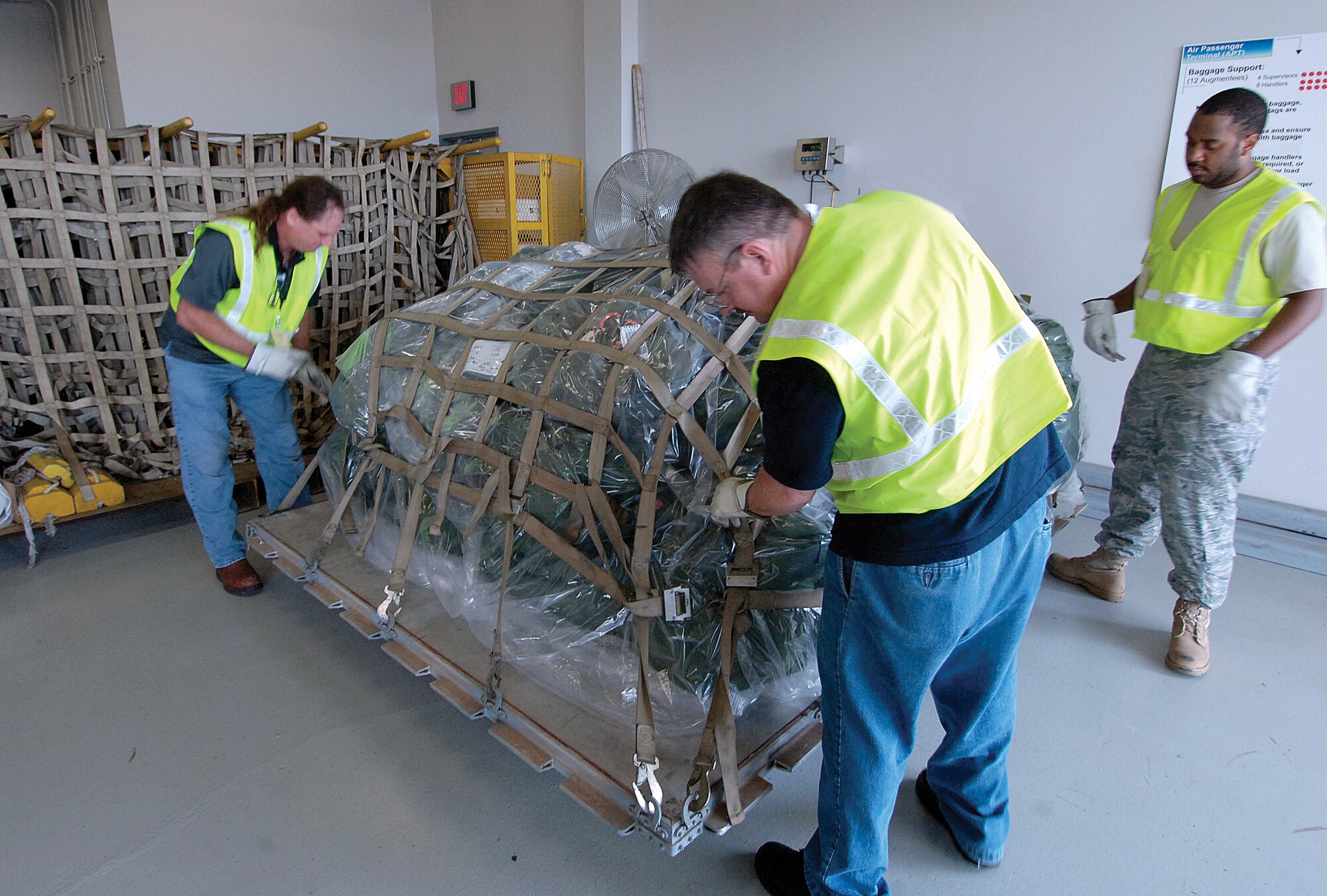 A mound of personal bags is secured on a pallet during a recent exercise here at Tinker.  Donnie Hunt, Robert Moore, and Christian Mullins, all with the 72nd Force Support Squadron, handle the 2,100 pounds of gear. (Air Force photo by Margo Wright) 