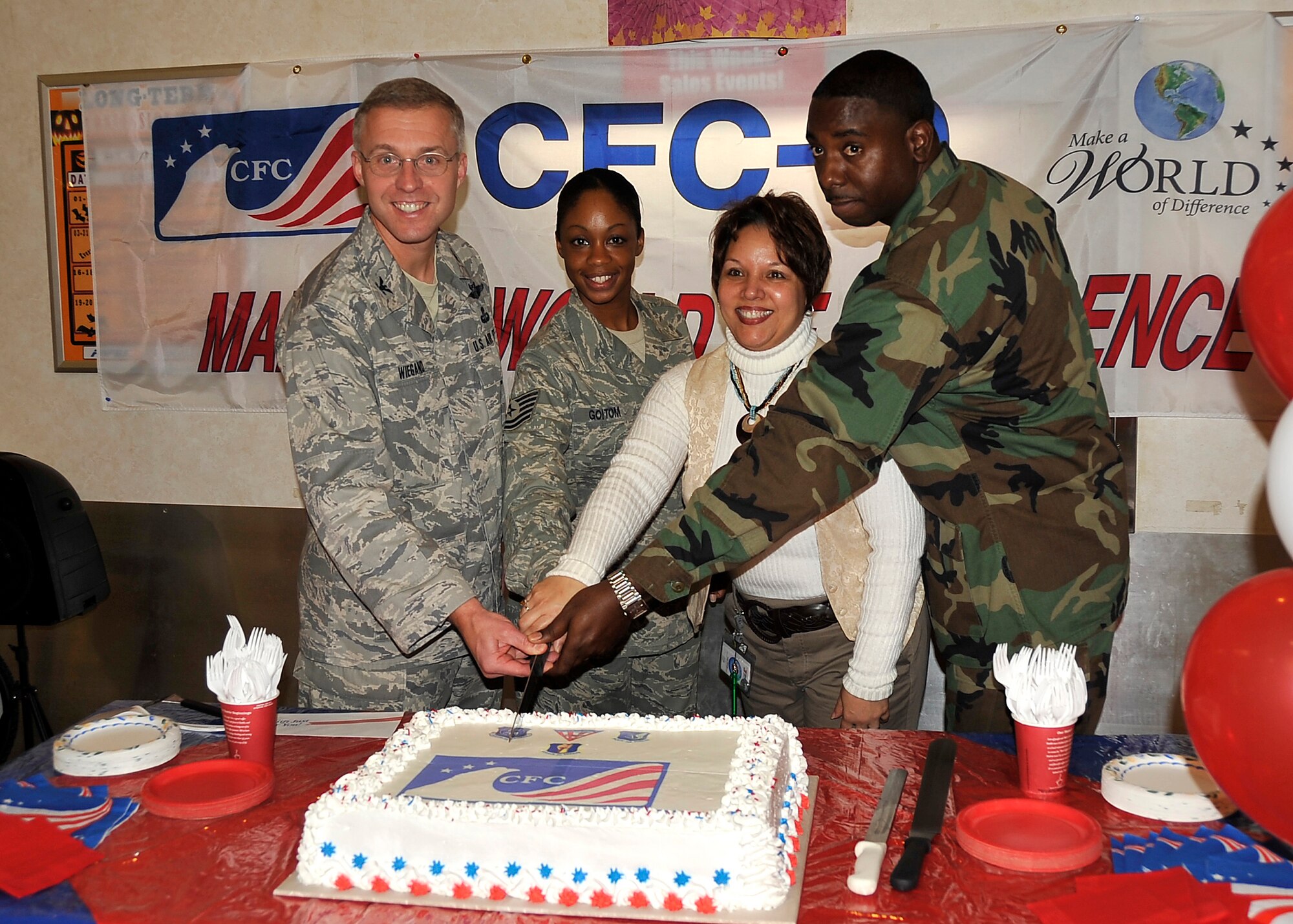 MISAWA AIR BASE, Japan -- Col. David Wiegand, 35th Mission Support Group commander, Staff Sgt. Awet Goitom, 35th Force Support Squadron Falcon Feeder dining facility manager, Rita Inchaurregui-Powell, Army & Air Force Exchange Service sales and merchandise manager, and Chief Petty Officer Ahmed Wiggins, Naval Air Facility security trainer chief, cut the ceremonial cake, marking the beginning of the Combined Federal Campaign-Overseas Oct. 2 at the base exchange. The CFCO consolidates all charitable solicitations into one campaign, once a year, lowering costs for participating charities and making it easier for federal employees to donate. (U.S. Air Force photo/Staff Sgt. Chad C. Strohmeyer)