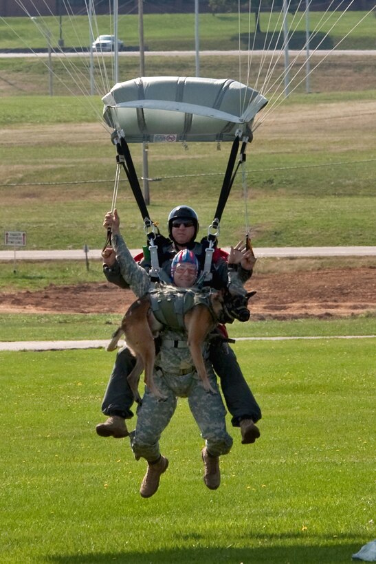 U.S. Army 1st Sgt. Chris Lalonde, center, holds onto his military working dog, Sgt. Maj. Fasco, and jumpmaster Kirby Rodriguez, behind them, land onto Gammon Parade Field, after making history with the military’s first tandem airborne jump from an altitude of 12,500 feet during Military Police Warfighter Week, Fort Leonard Wood, Mo., Sept. 18, 2009. Lalonde is assigned to Company D, 701st Military Police Battalion, and Rodriguez is assigned to the 342nd Training Squadron.
