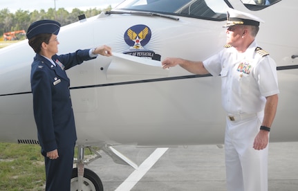 Col. Jacqueline Van Ovost, commander of the 12th Flying Training Wing, and Navy Capt. William Reavey, commander of Naval Air Station Pensacola, reveal the “Spirit of Pensacola” nose art on the 479th Flying Training Group flagship T-1A Jayhawk during the activation ceremony of the 479th FTG Oct. 2 in the National Museum of Naval Aviation at NAS Pensacola, Fla. (U.S. Air Force photo by Joel Martinez)