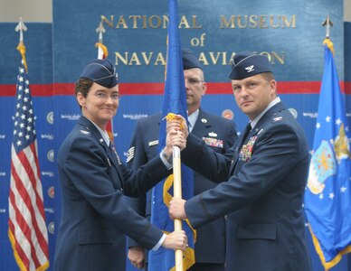 Col. Travis Willis accepts the unit flag to take command of the 479th Flying Training Group from Col. Jacqueline Van Ovost, commander of the 12th Flying Training Wing, Oct. 2 in the National Museum of Naval Aviation at Naval Air Station Pensacola, Fla. (U.S. Air Force photo by Joel Martinez)