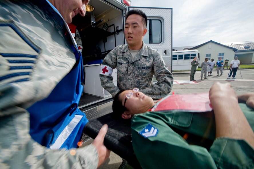 MISAWA AIR BASE, Japan -- Airman 1st Class Kang Kwon, 35th Medical Support Squadron out-patient records technician, assists Master Sgt. James Moore, 35th Medical Operations Squadron flight chief of diagnostic imaging, during a major accident response exercise Sept. 29 on the base flightline. During the exercise, the two were part of an AMBUS/manpower team and helped evacuate victims from the simulated crash site. (U.S. Air Force photo/Senior Airman Jamal D. Sutter)