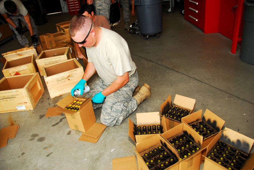 Munitions maintenance Senior Airman John Rench spray paints high intensity flares used on the F-16 Fighting Falcons.