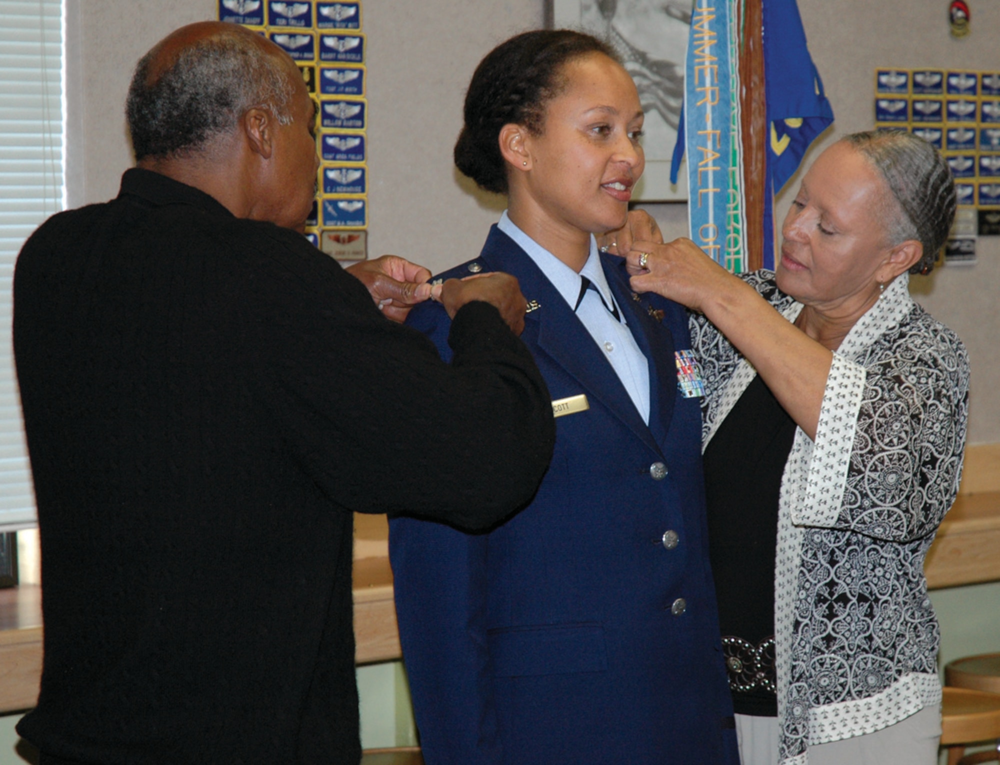 Leonard and Alma Scott pin new rank insignias on their daughter, Lt. Col. Kimberly Scott, 728th Airlift Squadron, during her promotion ceremony October 3, 2009.  Colonel Scott's pinning on ceremony included not only members of her immediate family, but also members of the Tuskegee Airmen.  Retired Lt. Col. Edward Drummond administered the oath of office. "Members of the Tuskegee Airmen have mentored, encouraged, and supported me over the years," said Colonel Scott. "It was incredibly meaningful to me to have been sworn in by him."