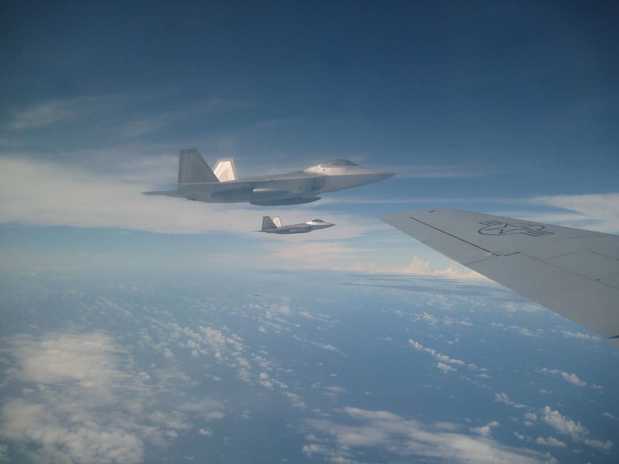 SEYMOUR JOHNSON AIR FORCE BASE, N.C. -- Two F-22s Raptors off the tip of a 916th Air Refueling Wing KC-135R near Guam.