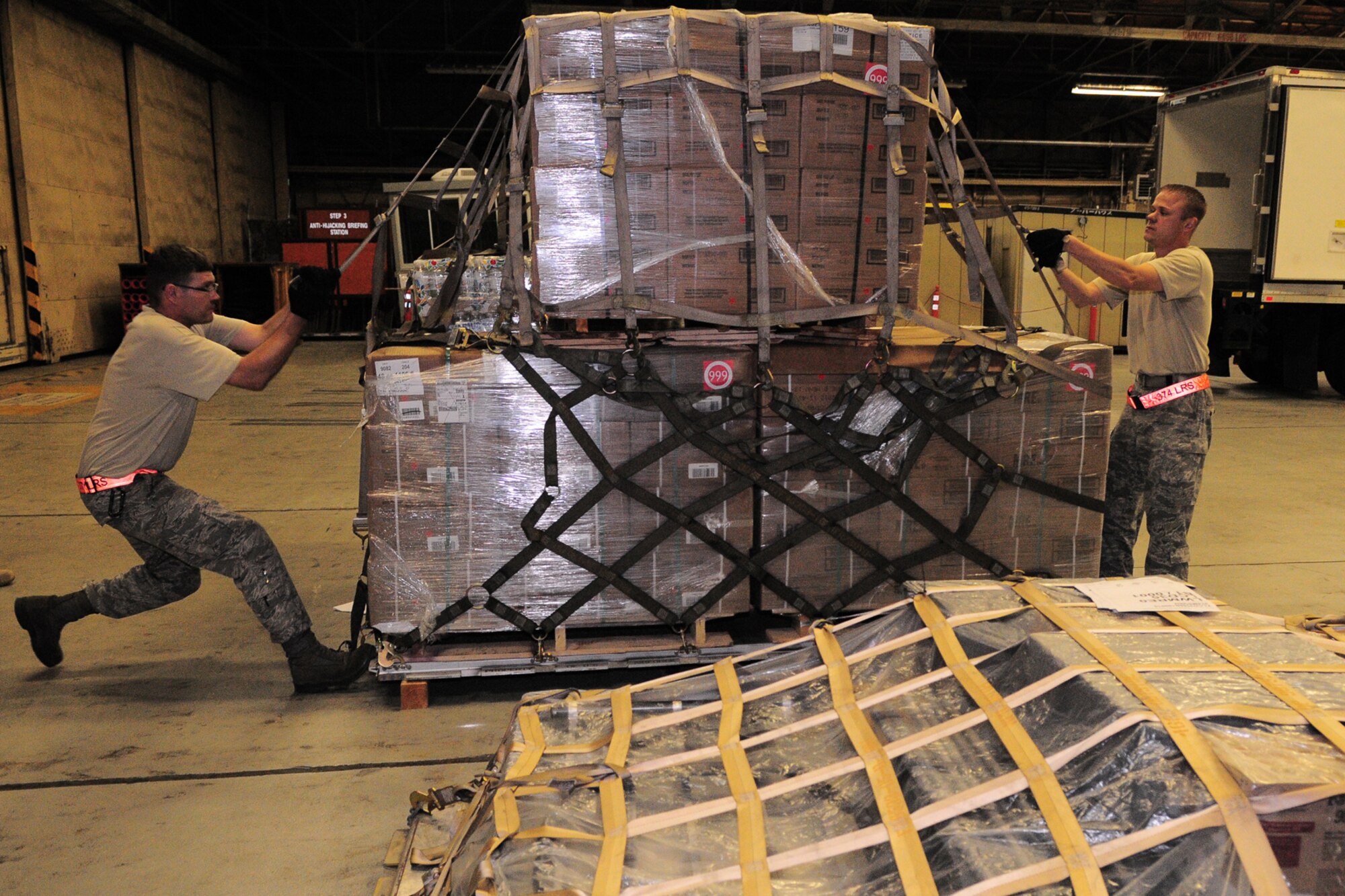 YOKOTA AIR BASE, Japan -- Tech. Sgt. Robert Davis and Tech. Sgt. Chris Peters, 374th Logistics Readiness Squadron, tighten the straps on a pallet of supplies Oct. 3 in support of the deployment of a U.S. Air Force Humanitarian Assistance Rapid Response Team to Padang, Indonesia. Sergeant Peters helped to build nine pallets totaling more than 35,000 pounds of equipment. The HARRT, which includes members from here and Andersen Air Force Base, Guam, is scheduled to depart Oct. 5 aboard a C-17 Globemaster III. (U.S. Air Force photo/Airman 1st Class Michael Dillon)
