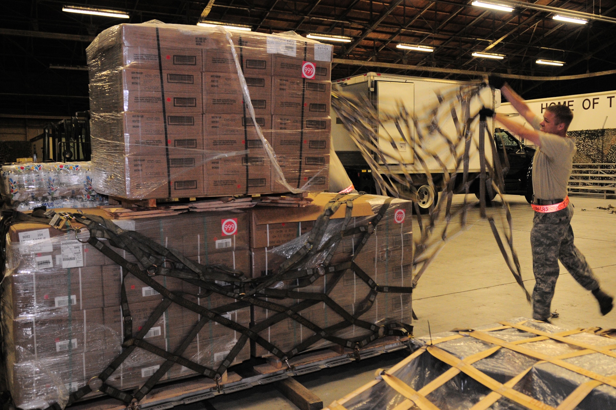 YOKOTA AIR BASE, Japan -- Tech. Sgt. Chris Peters, 374th Logistics Readiness Squadron, tosses a net over a pallet of supplies Oct. 3 in support of the deployment of a U.S. Air Force Humanitarian Assistance Rapid Response Team to Padang, Indonesia. Sergeant Peters helped to build nine pallets totaling more than 35,000 pounds of equipment. The HARRT, which includes members from here and Andersen Air Force Base, Guam, is scheduled to depart Oct. 5 aboard a C-17 Globemaster III. (U.S. Air Force photo/Airman 1st Class Michael Dillon)