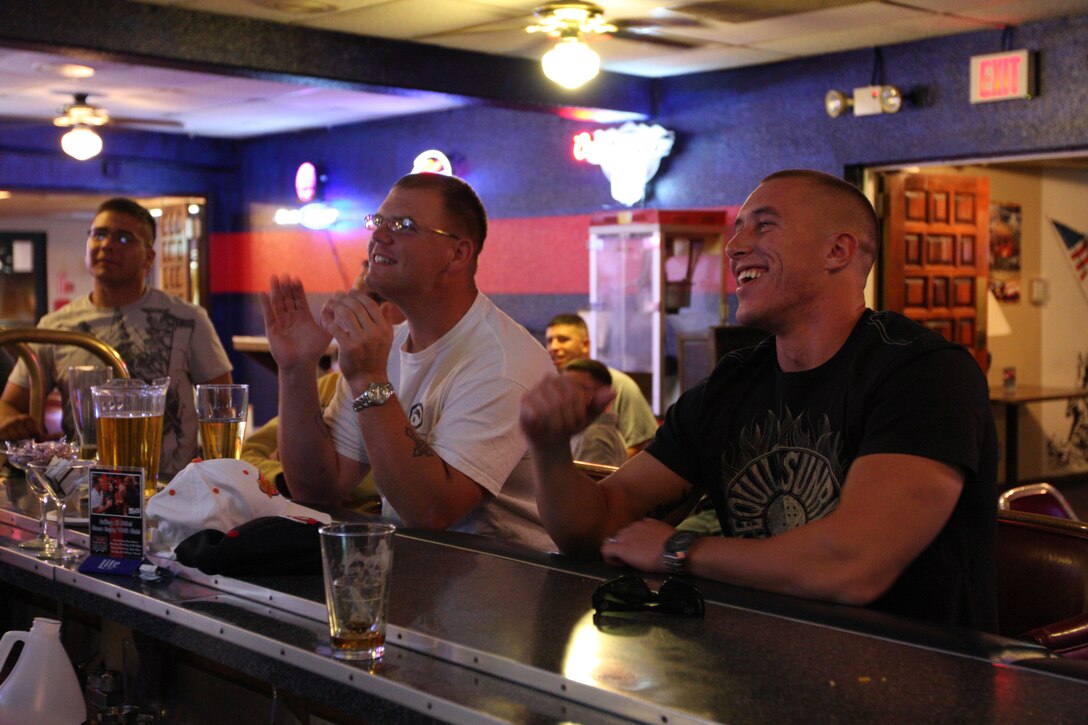 Cpl. Matthew Tri (left), a mortorman with 7th Marine Regiment, and Cpl. Jordan Anderson, a data NCO with 1st Marines, 12th Marine Regiment, from Marine Corps Base Hawaii, celebrate as they watch their football team make a good play at the Combat Center's Bloodstripes NCO Club Oct. 5.