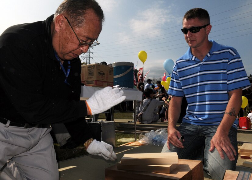 Mr. Masaichi Adachi, a wood-work master, shows Staff Sgt. James Bierman, from the 18th Equipment Maintenance Squadron at Kadena Air Base, Japan, tries his hand at Kibori (wood working) at a local farm festival during the visit to Hyakuri Air Base, Japan, Oct. 04. The squadron is participating in an Aviation Training Relocation exercise between the U.S. Air Force and the Japan Air Self Defense Force from Oct. 5-9, 2009.