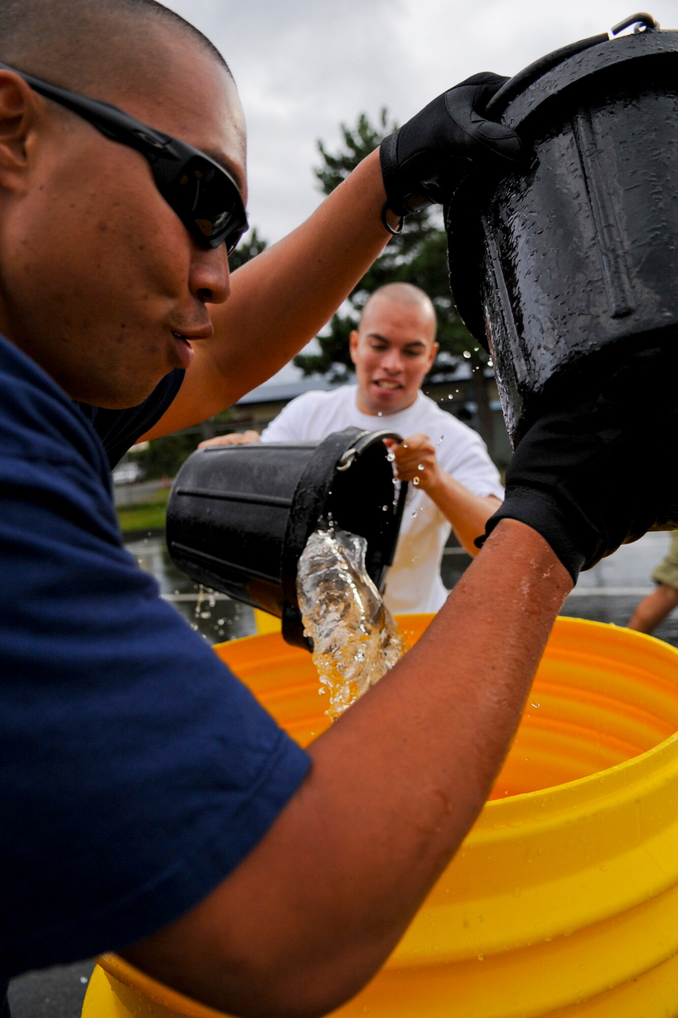 MISAWA AIR BASE, Japan -- Senior Airmen Steven Saulo and Christian Sandavol, both 35th Civil Engineer Squadron firefighters, participate in a bucket brigade competition during the Misawa Air Base Fire Muster Oct. 4 at the Base Exchange. Other competitions included a truck pull, relay competition and water-ball competition. (U.S. Air Force photo by Senior Airman Jamal D. Sutter)