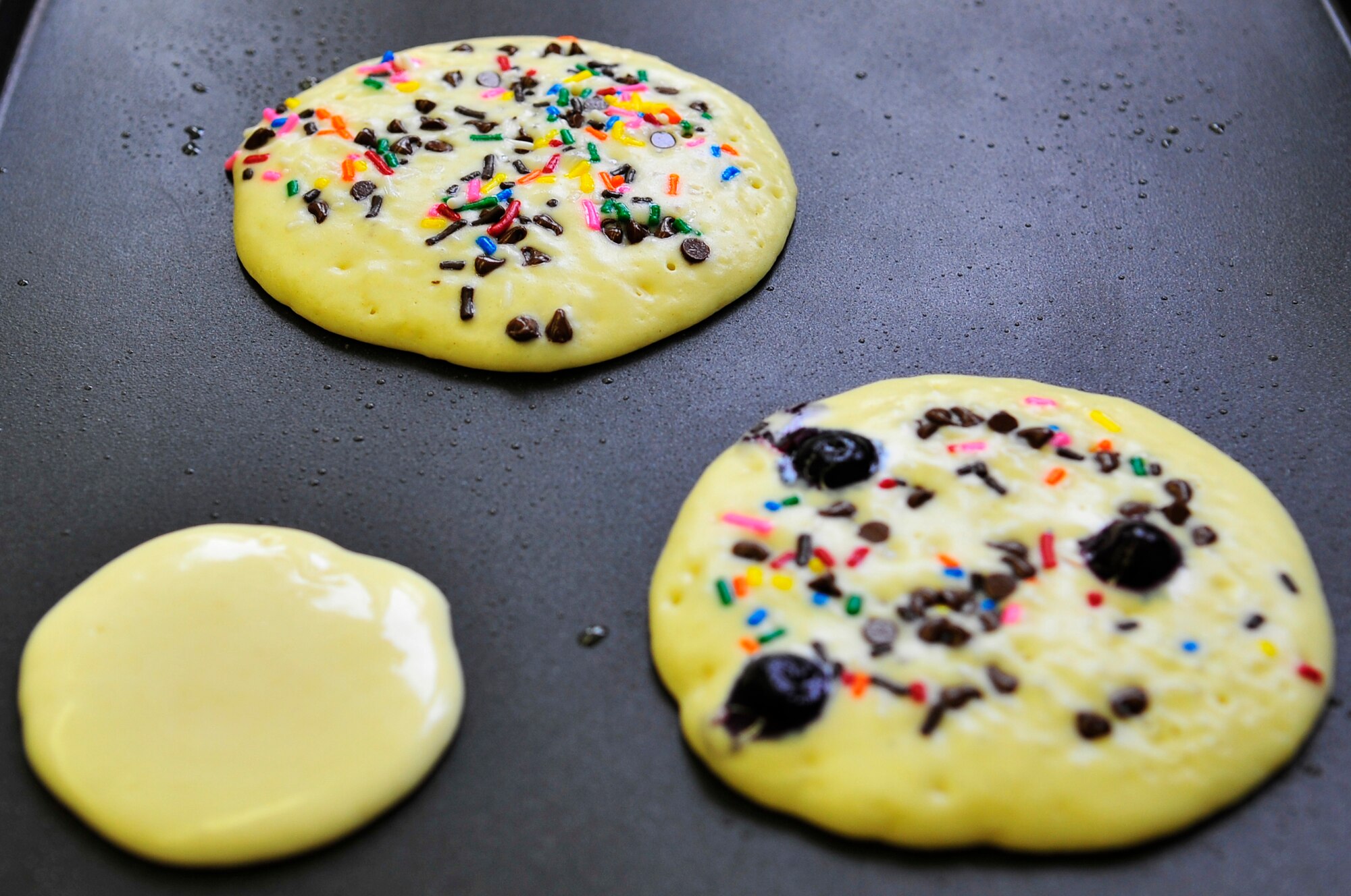 Pancakes, decorated with sprinkles, chocolate chips and berries, cook on a griddle at the library during the 2nd annual "Book 'Em and Cook 'Em" program Oct. 3, 2009, Eielson Air Force Base, Alaska. The program entertained more than 40 children who were read stories and then prepared the meal that was read to them. (U.S. Air Force photo/Staff Sgt. Christopher Boitz)