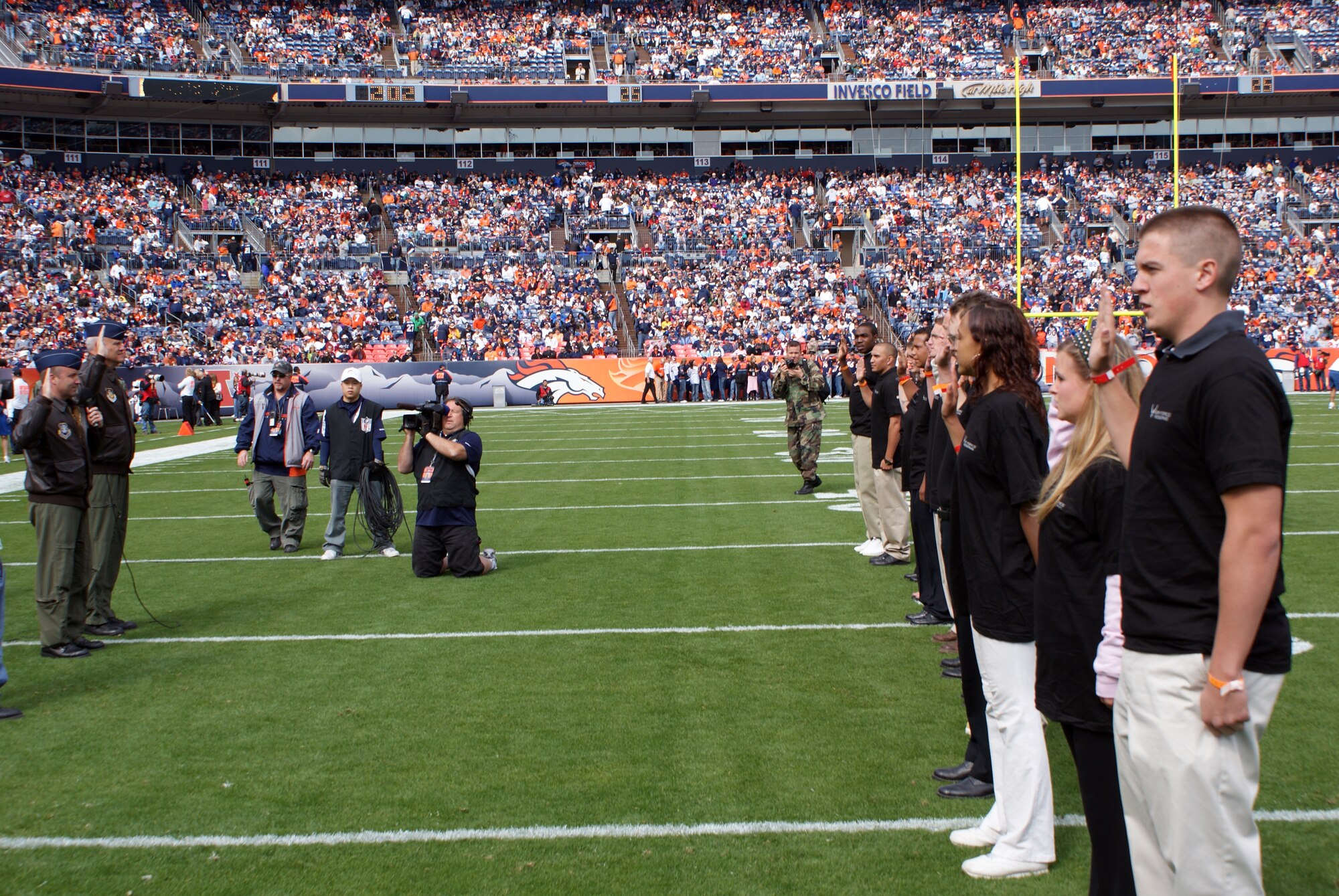 310th Space Wing vice commander Col. Mark D. Hustedt administers the oath of enlistment to new Air Force Reserve enlistees on center field before the Denver Broncos game Oct. 4 in Denver, Colo. (U.S. Air Force photo/Tech. Sgt. Benjamin D. Millspaugh)