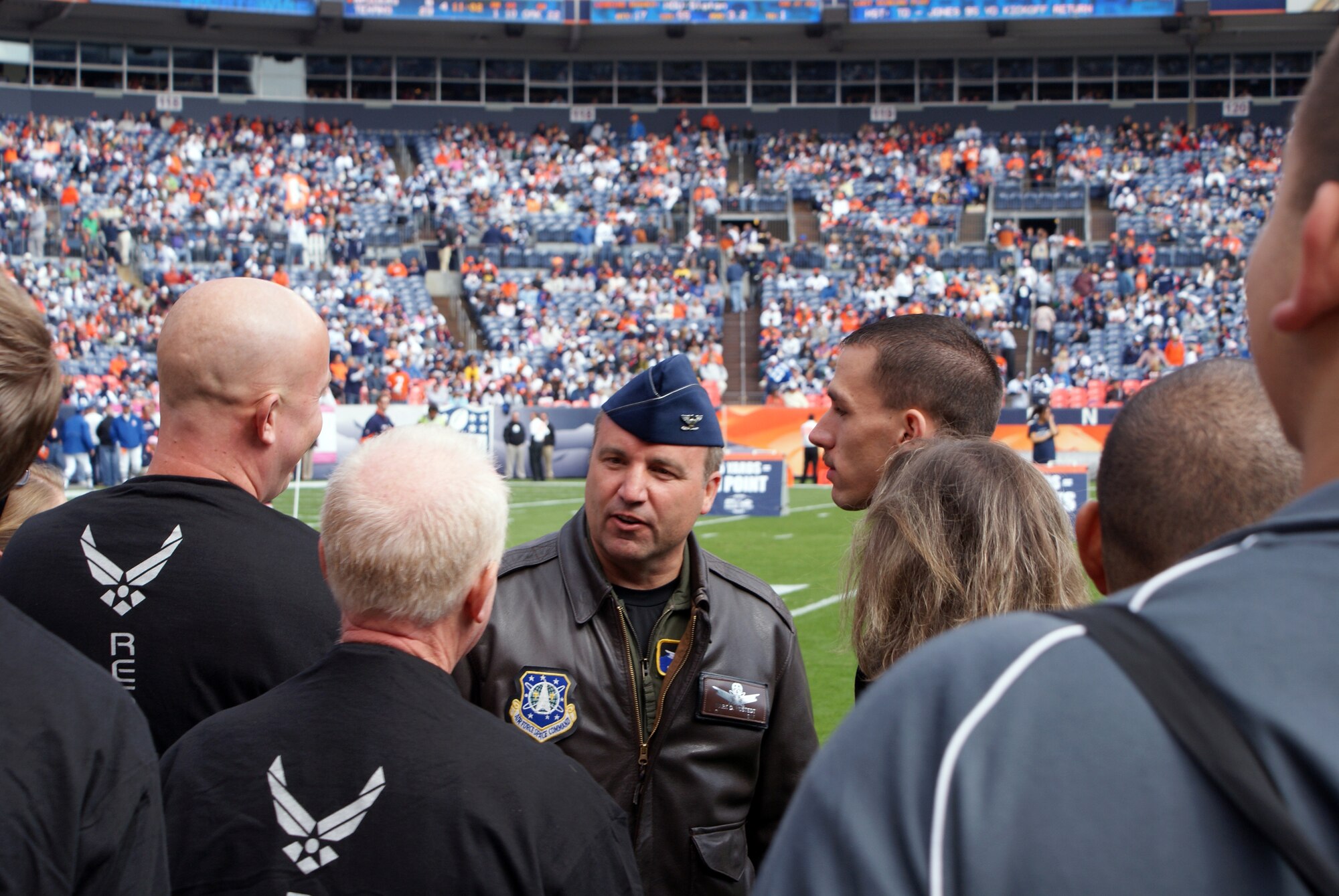 310th Space Wing vice commander Col. Mark D. Hustedt talks with new Air Force Reserve enlistees before they take the oath of enlistment on center field before the Denver Broncos game Oct. 4 in Denver, Colo. (U.S. Air Force photo/Tech. Sgt. Benjamin D. Millspaugh)