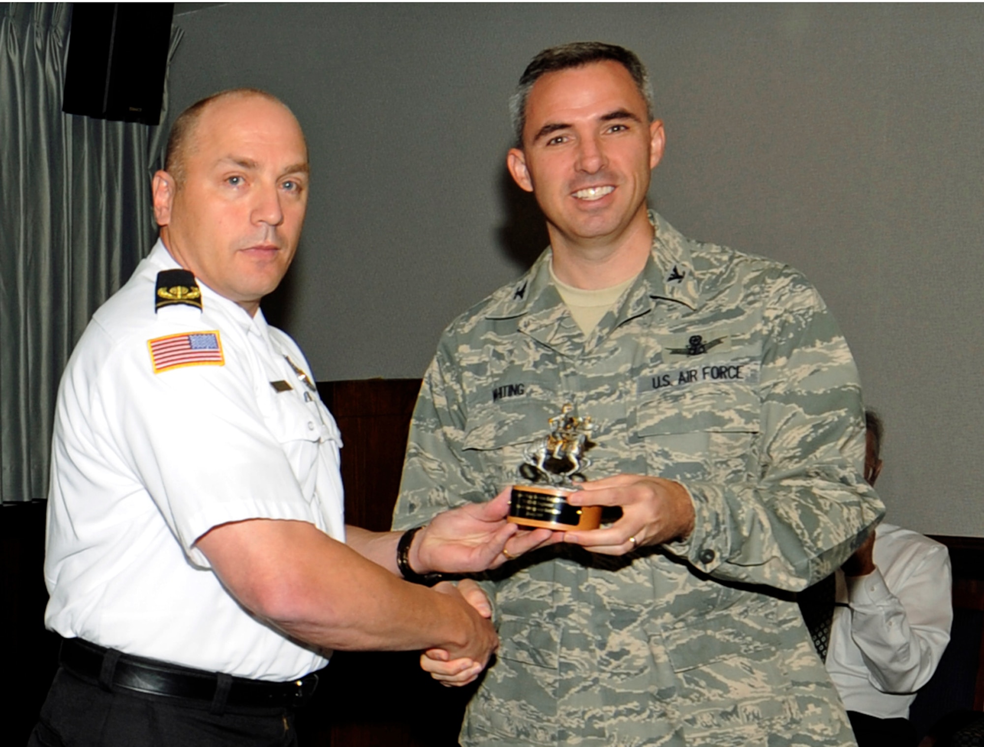 PETERSON AIR FORCE BASE, Colo. -- Chris Miller, 721st Mission Support Group fire chief, accepts the Golden Knight award from Col. Stephen Whiting, 21st Space Wing commander, during wing standup Sept. 29. The 721st Civil Engineer Fire and Emergency Services team at Cheyenne Mountain Air Force Station was selected to receive the Golden Knight Award for creating the first-ever regional Department of Defense Wildlife Academy. Team members include: Mr Miller, Dale Ross, David Arcilla, Christopher Soliz, Justin Ochsendorf, Marshall Munger, Reid Lohse, Joshua Lorber, Elias Kunishige, Joshua Sexton, Richard Burgess, Chad Staggs, Paul Vigeant, Robert Johnson, David Pritchard, Donald Winans, Christopher Smith, Matthew Backeberg, Brian Zimmerman, Jonathan Sprague, Charles Surratt, Raymond Begnaud, Ryan Moriarty, Eric Miller, Steve Kjonaas and Rebecca Winans. The Golden Knight Award recognizes 21st Space Wing teams on a monthly basis for their efforts and leadership in the local community. (Air Force photo by Rob Bussard)