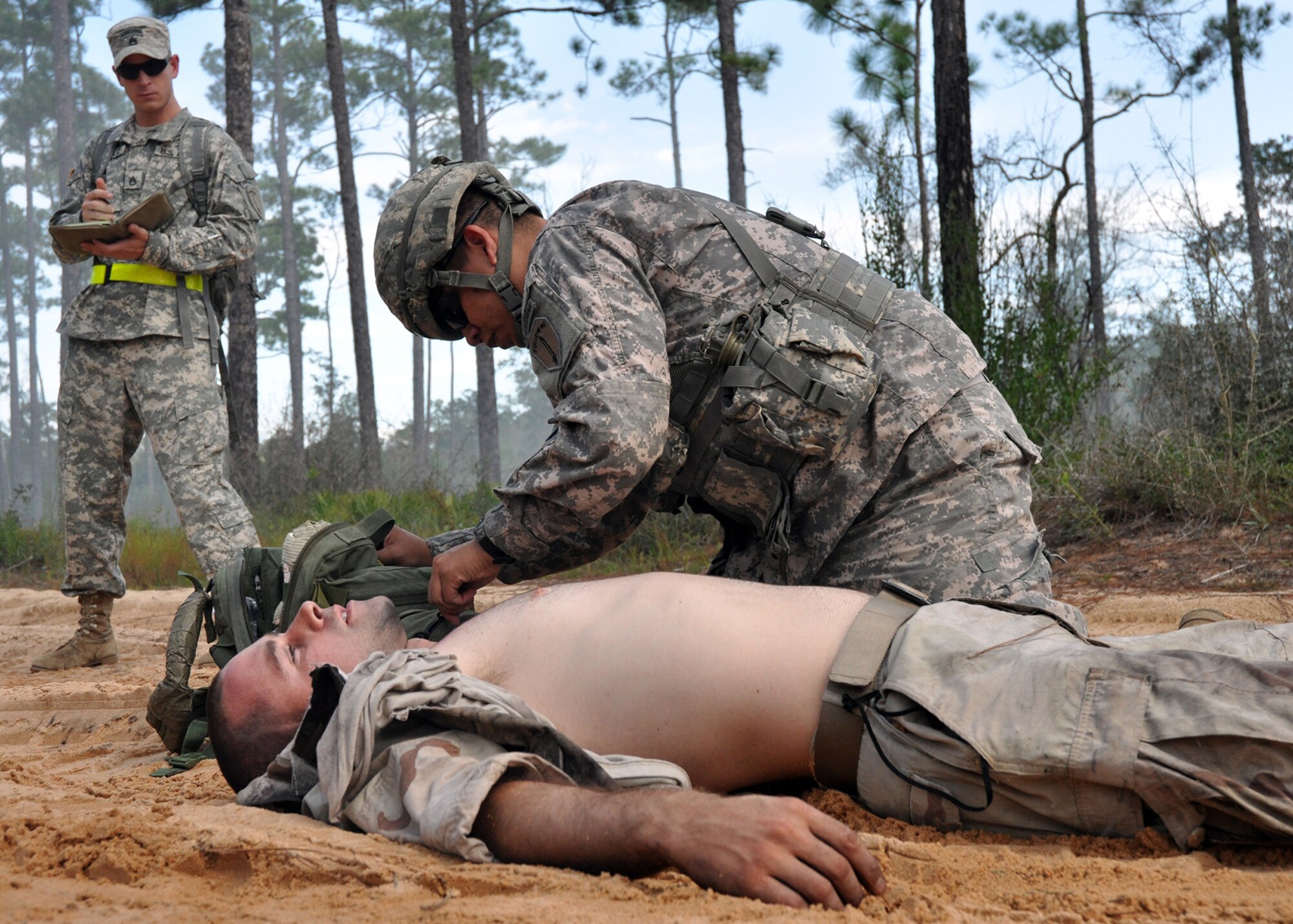 Spc. Ian Jones, 6th Ranger Training Battalion medic, provides medical attention to a simulated car accident victim Oct. 1 during the 6th RTB's annual mass casualty exercise.  An Army evaluator watches and notes the Soldier’s procedures. The exercise was to examine how effective the battalion responds as a group and how well it communicates and works with outside emergency agencies in the event of a catastrophe on Eglin's range.  (U.S. Air Force photo/Airman Anthony Jennings.)